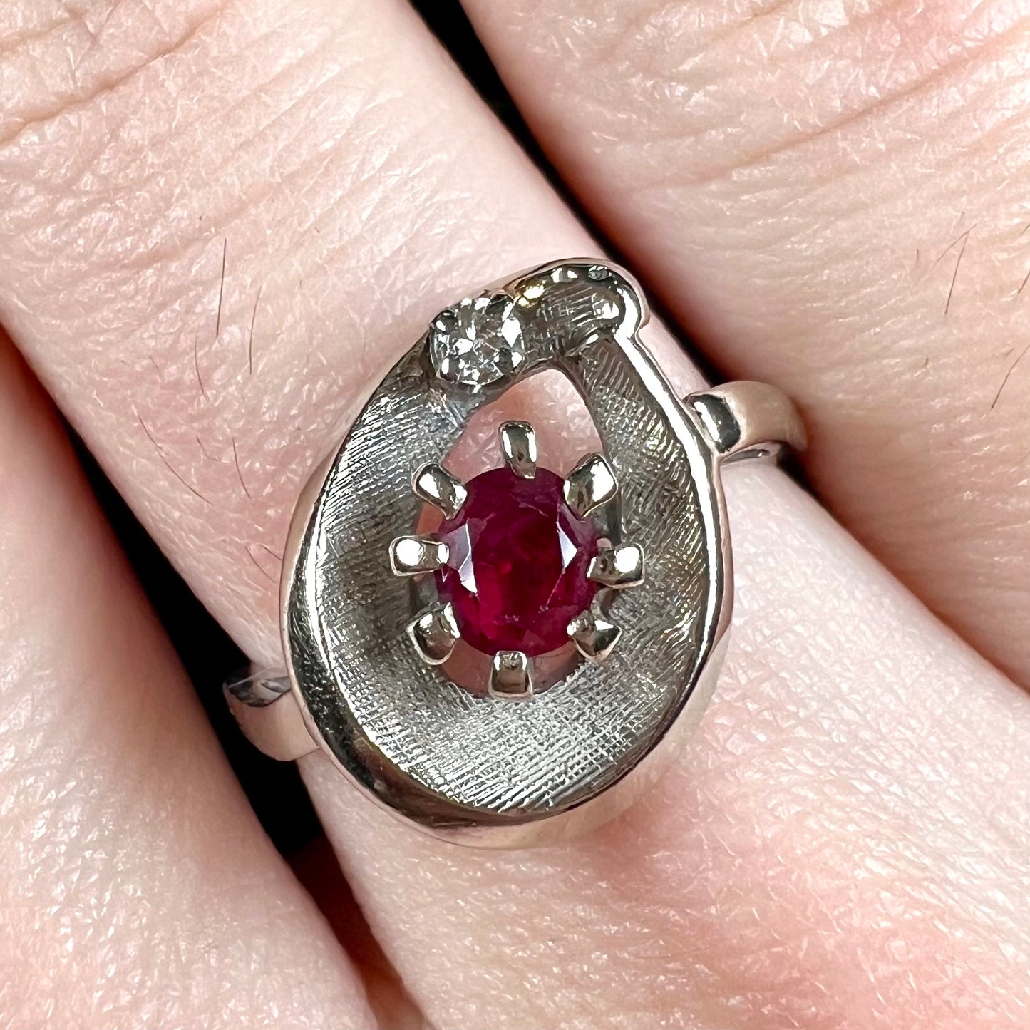 A ladies' estate white gold ruby ring set with a diamond accent stone.