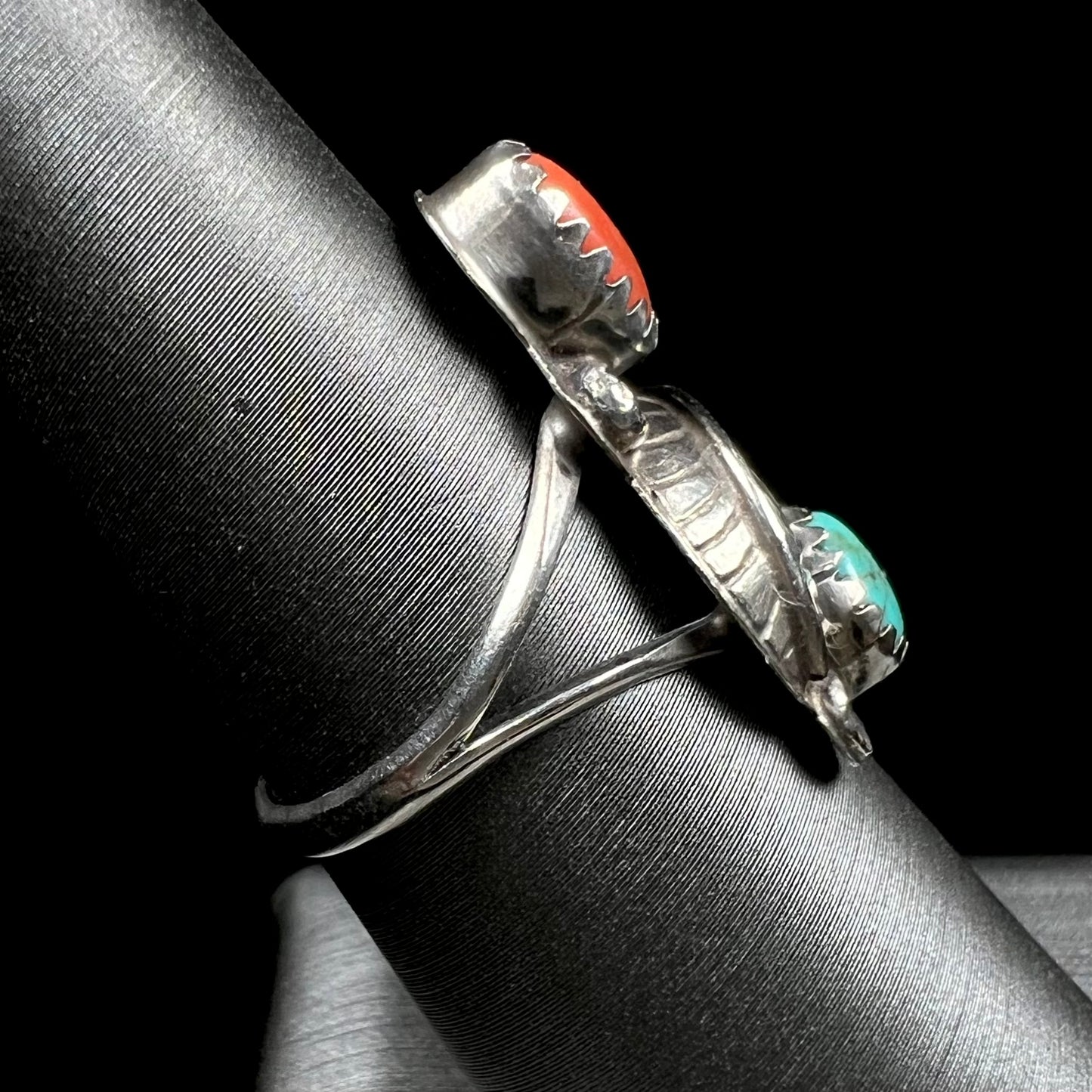 A vintage sterling silver Navajo style ring set with turquoise and coral stones and a feather design.