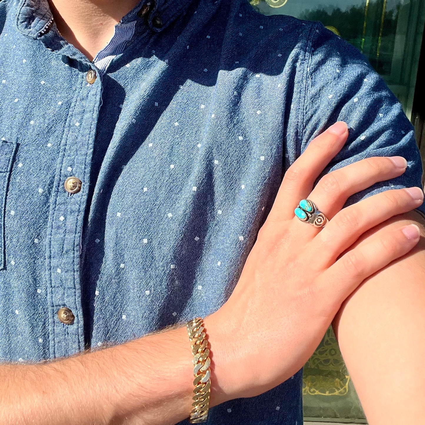 A unisex sterling silver ring bezel set with two Pilot Mountain turquoise stones.  The ring is stamped with sun patterns.