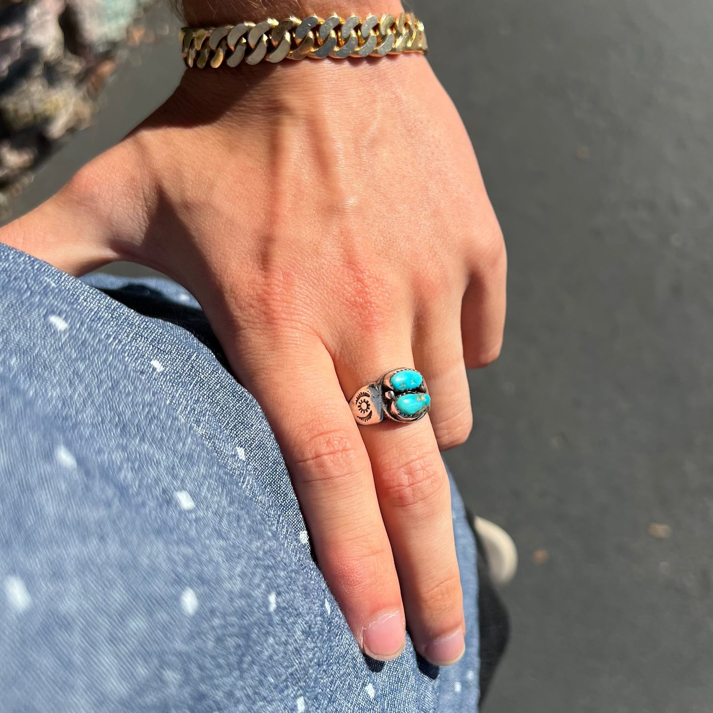 A unisex sterling silver ring bezel set with two Pilot Mountain turquoise stones.  The ring is stamped with sun patterns.