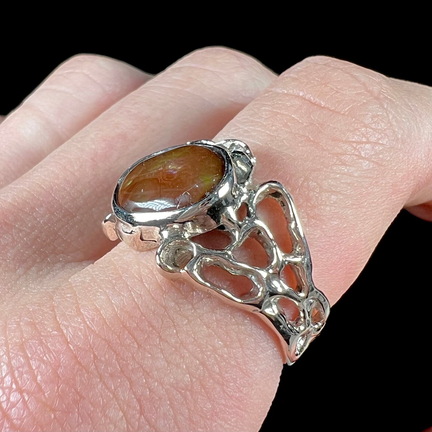 An organic-style white gold men's ring, bezel set with an oval cut Mexican fire agate stone.  The stone is green and purple.