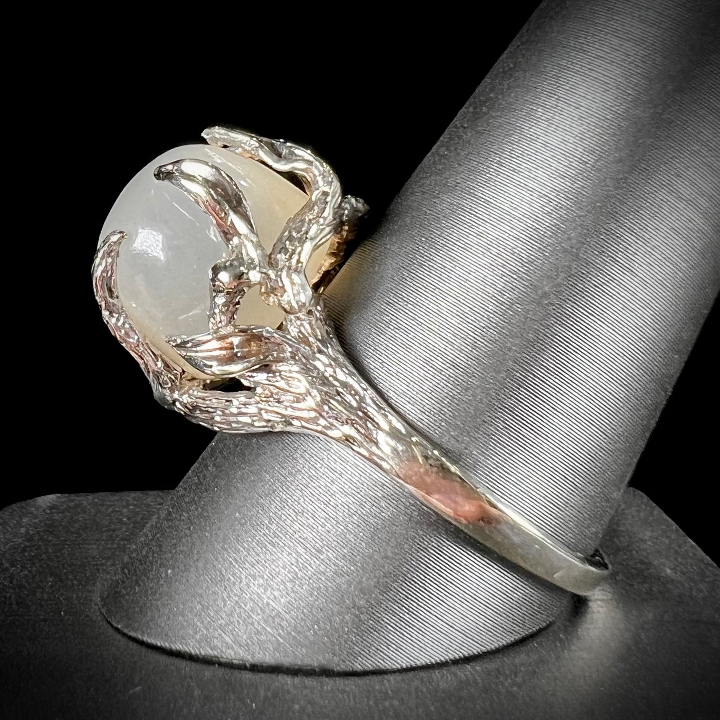 A ladies' organic style white gold moonstone ring. The moonstone shows white adularescence on a creamy white body color. Prongs resemble leaves holding the stone.