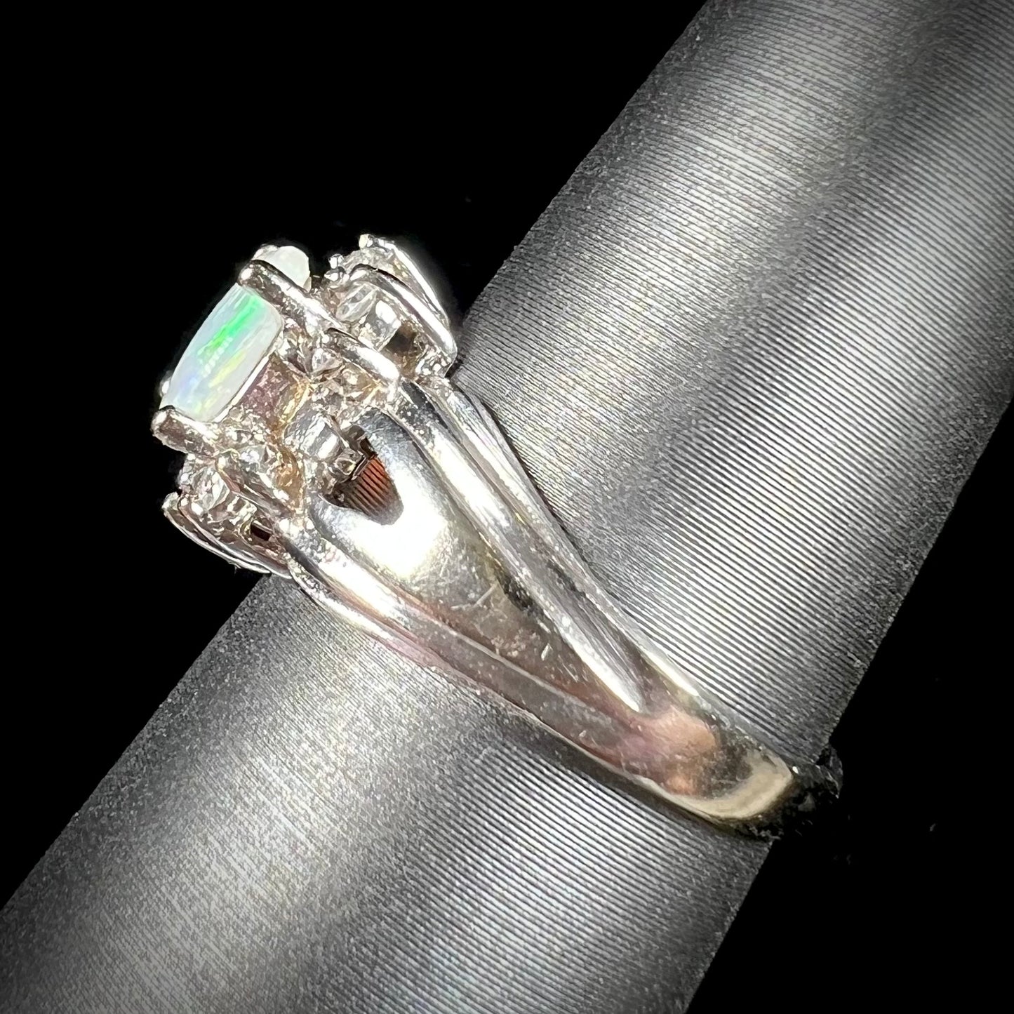 A ladies' white gold ring set with a halo of diamonds and an oval cabochon cut Australian opal.
