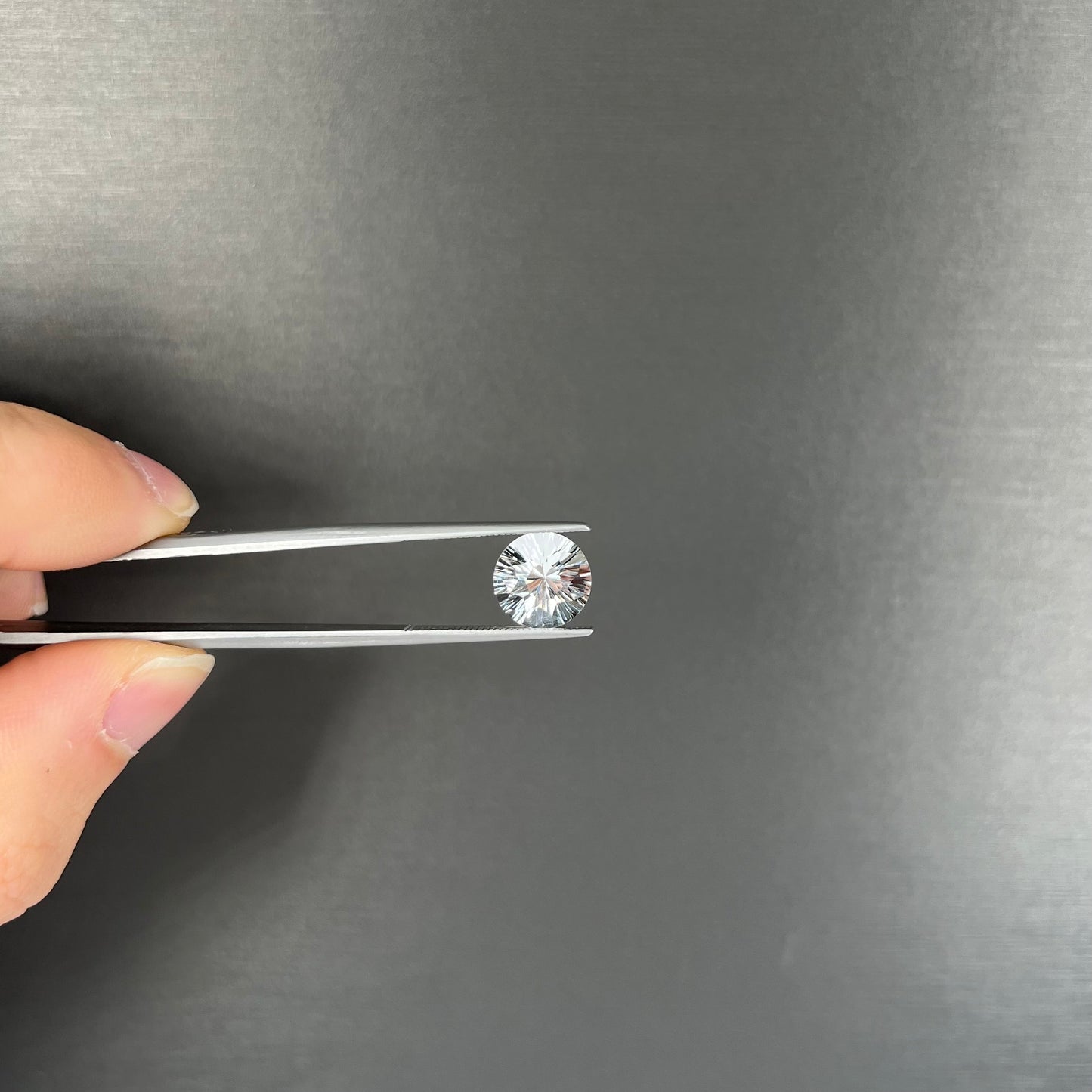 A round brilliant cut petalite gemstone. The stone is colorless.