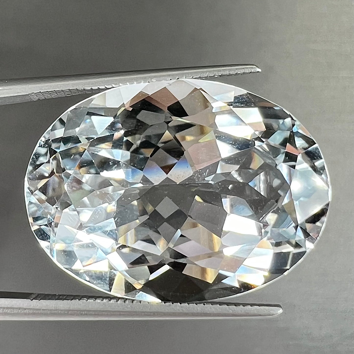 A loose, faceted oval cut white topaz gemstone. The stone is large in size.