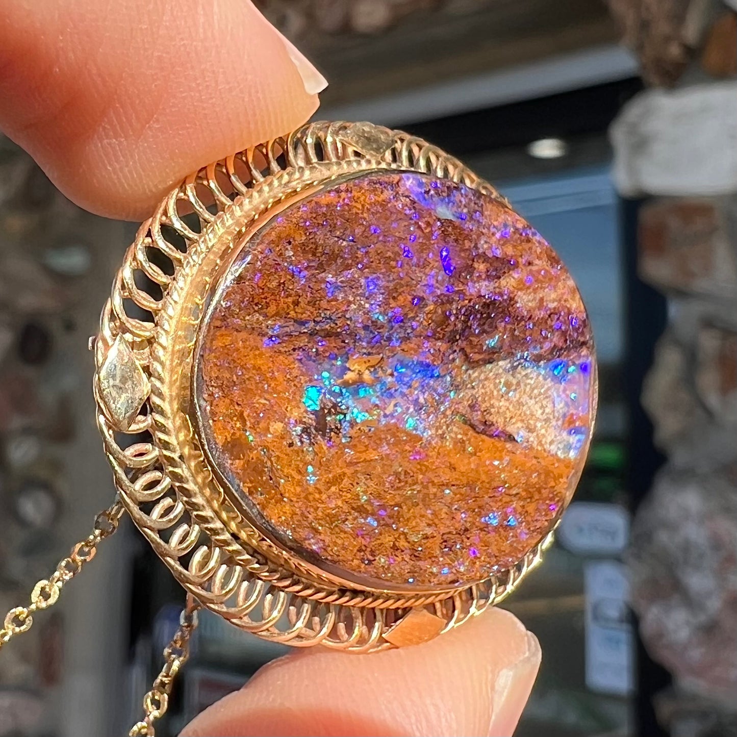 A yellow gold filigree style brooch/pendant combination piece set with a purple opalized wood stone from Duck Creek, Australia.