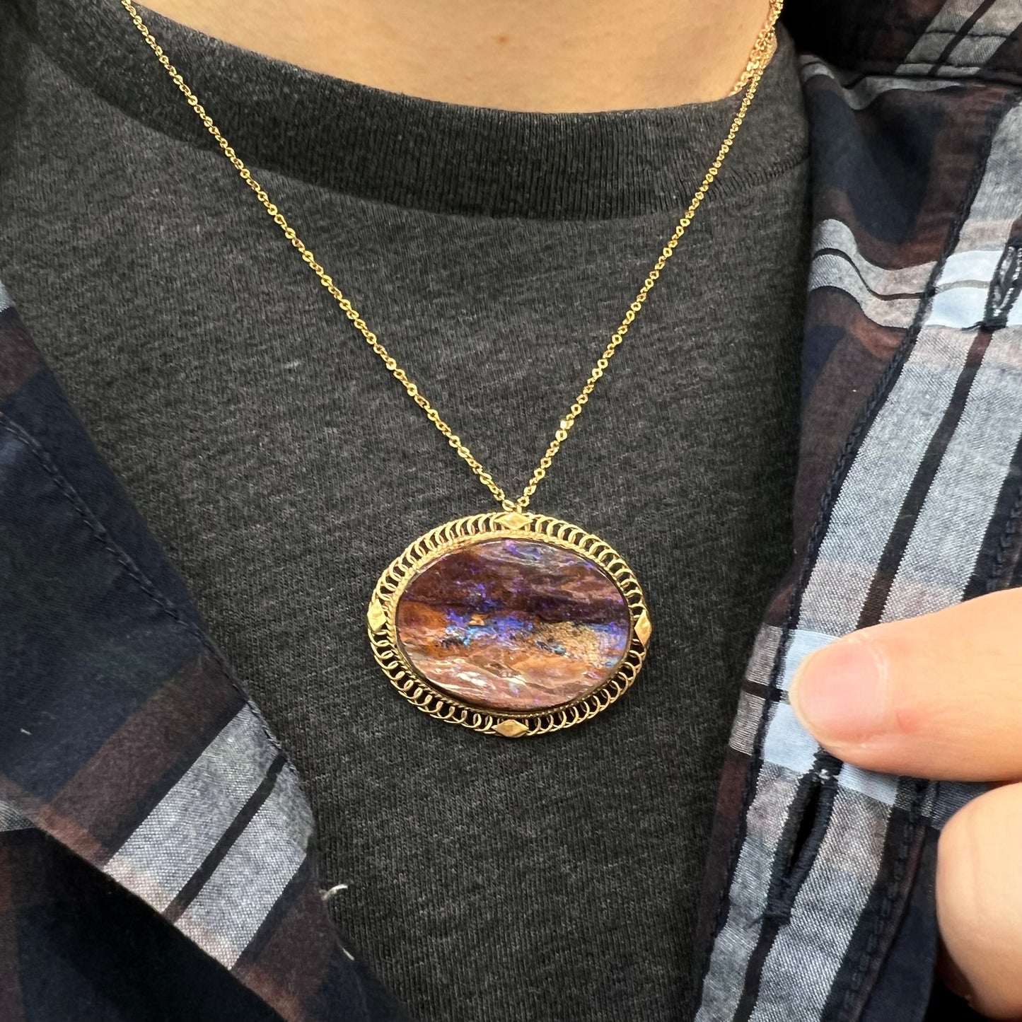 A yellow gold filigree style brooch/pendant combination piece set with a purple opalized wood stone from Duck Creek, Australia.