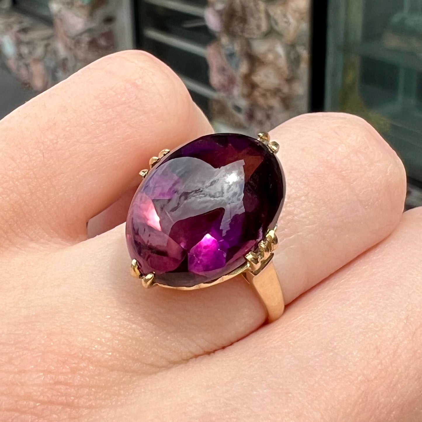 A ladies' 18 karat yellow gold oval cabochon cut amethyst ring. The ring is 1920's style.