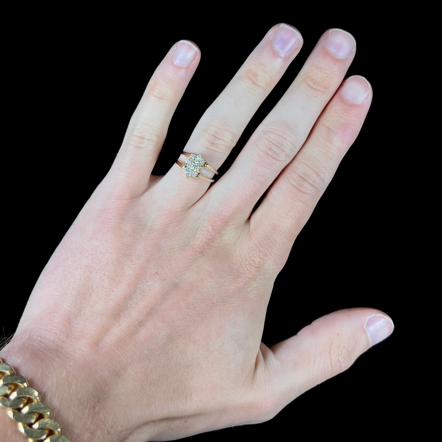 A yellow gold reversible gemstone flip ring. One side of the ring shows a green gemstone, the other shows a cluster of cubic zirconia.