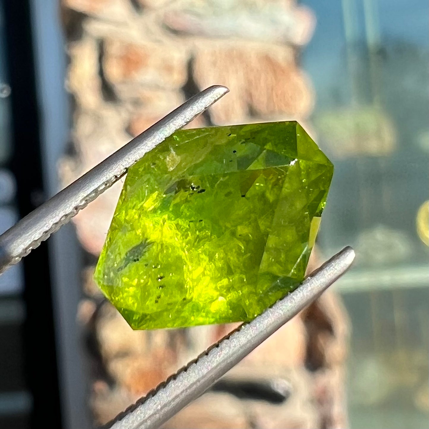 A loose, modified octagon peridot stone. The stone is a yellow green color.