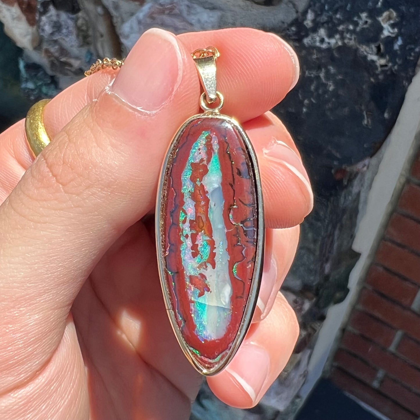 A yellow gold pendant set with a natural Yowah nut boulder opal stone.