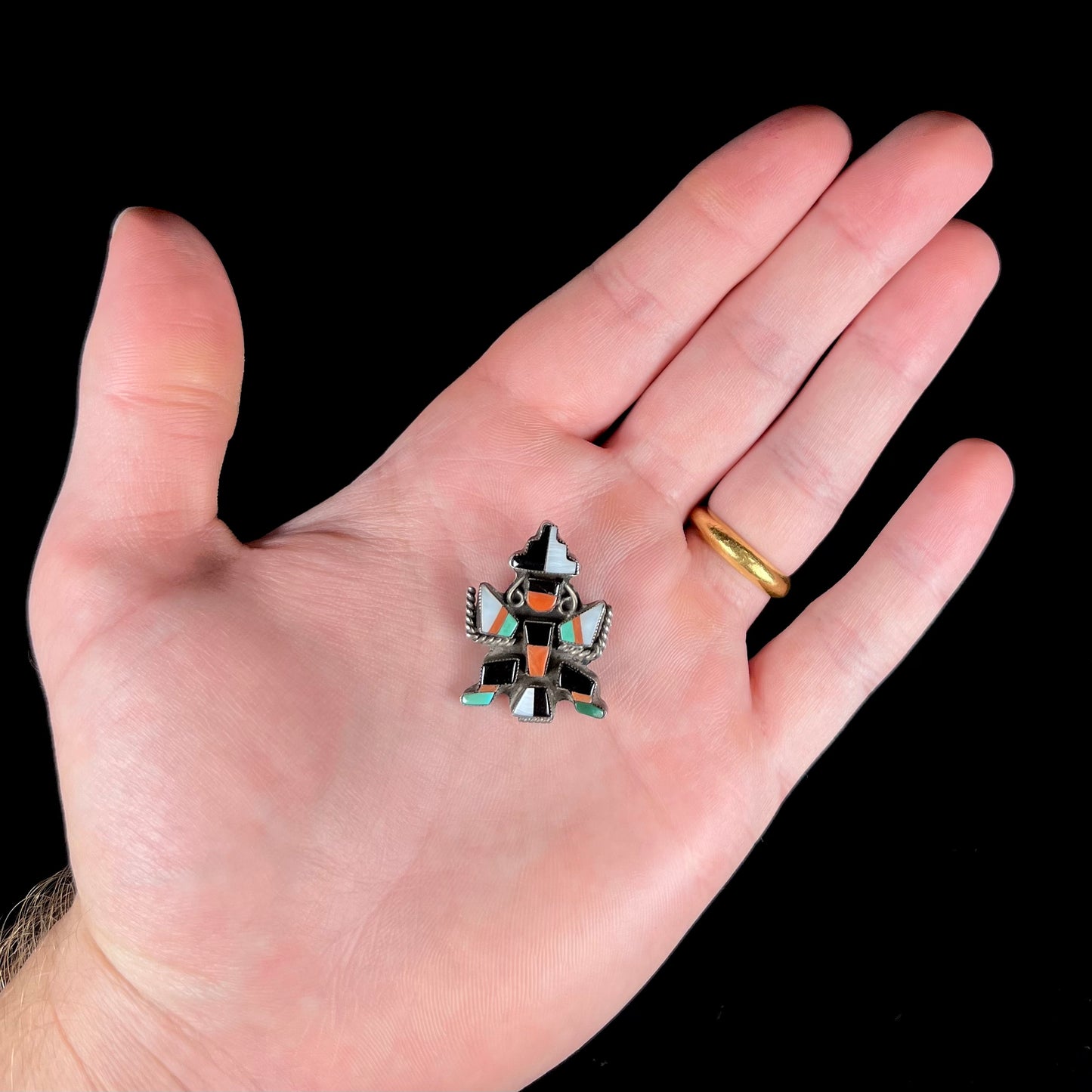 A sterling silver brooch depicting a Zuni Indian knifewing dancer, inlaid with jet, turquoise, coral, and mother of pearl.
