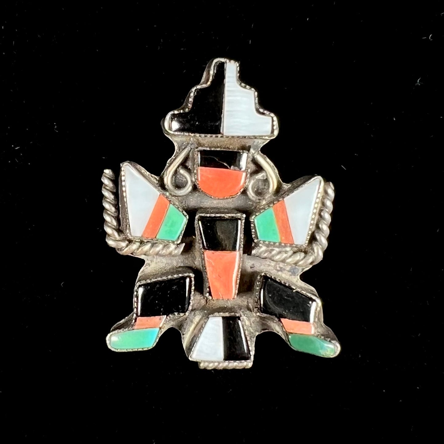 A sterling silver brooch depicting a Zuni Indian knifewing dancer, inlaid with jet, turquoise, coral, and mother of pearl.