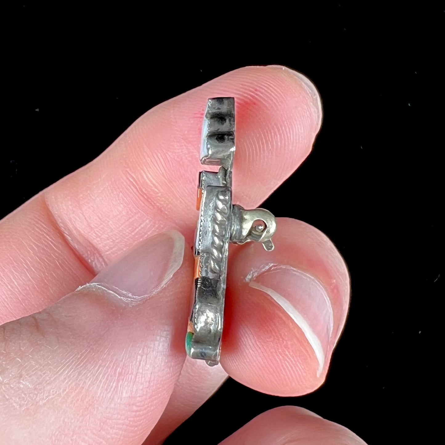 A sterling silver brooch depicting a Zuni Indian knifewing dancer, inlaid with jet, turquoise, coral, and mother of pearl.