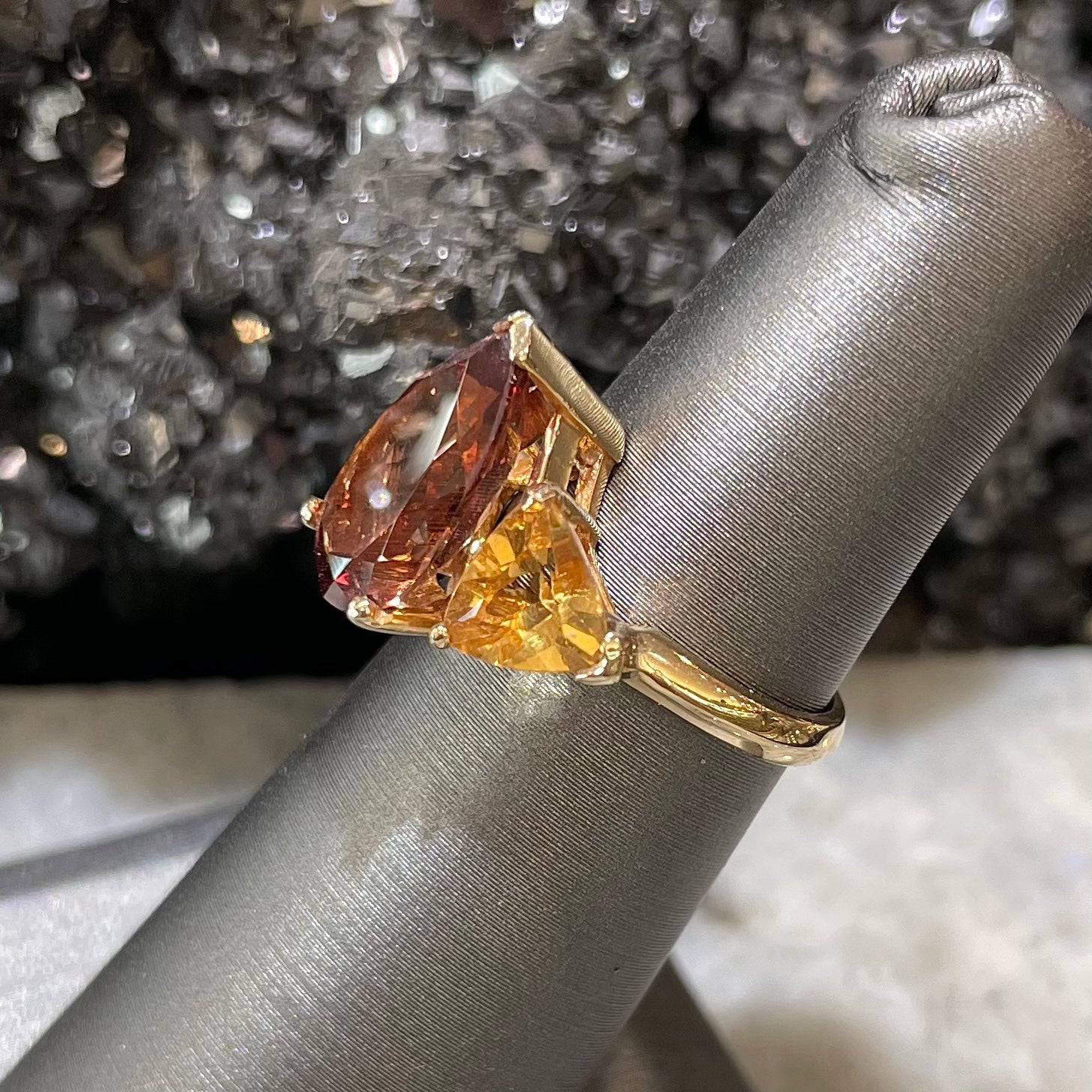A gold ring set with a pear shape color change garnet between two trillion cut citrine accent stones.