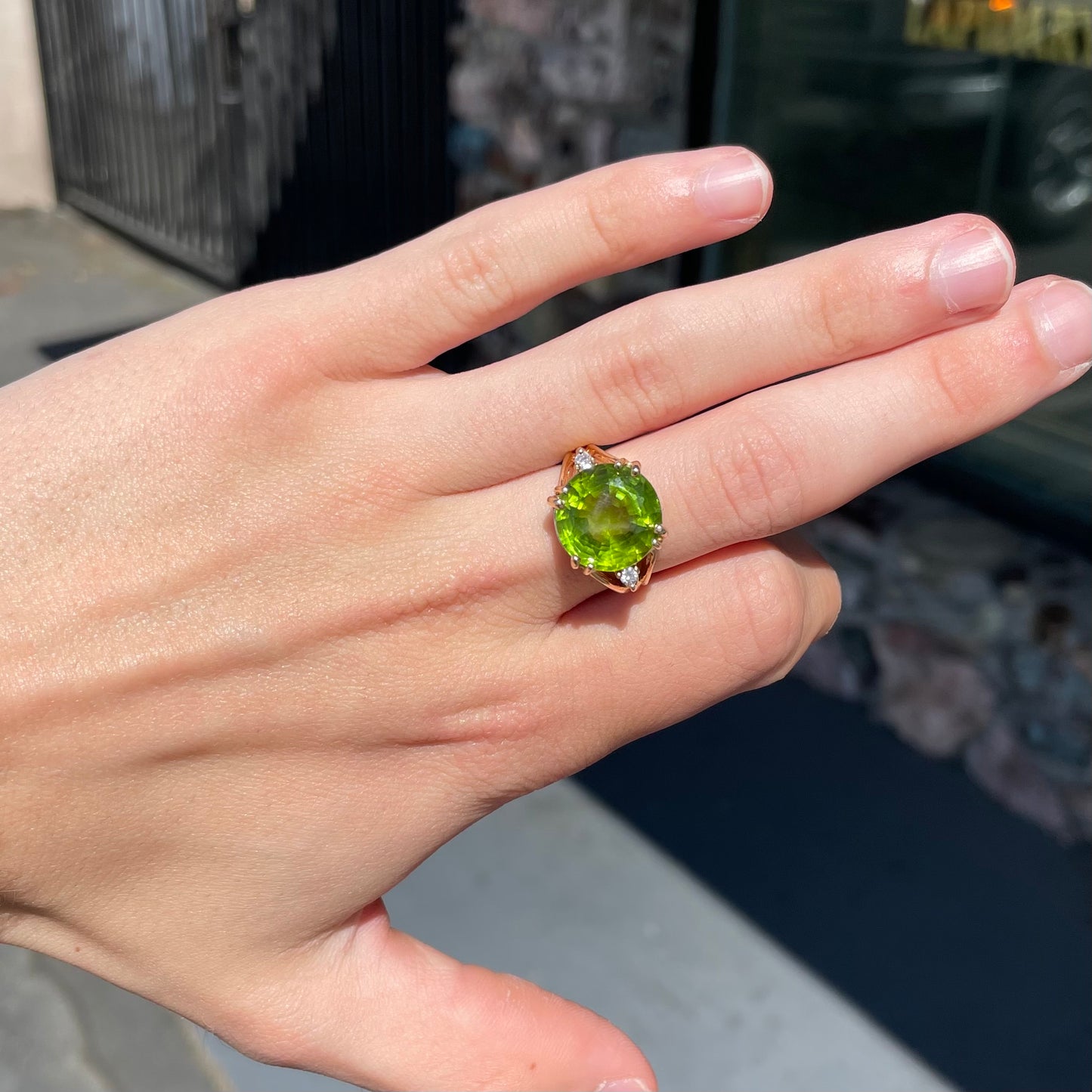 A ladies' round brilliant cut peridot statement ring set with two round diamond accents in yellow gold.