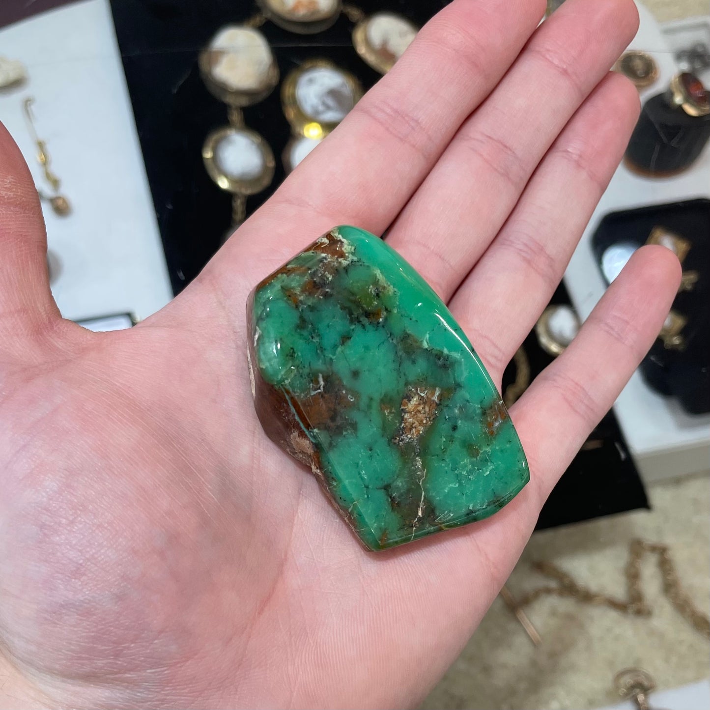 A polished green chrysoprase stone with brown matrix inclusions.