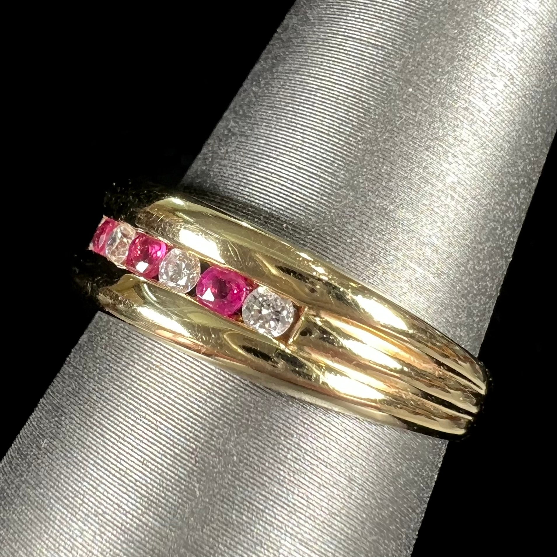 An 18kt yellow gold band channel set with round cut rubies and diamonds.