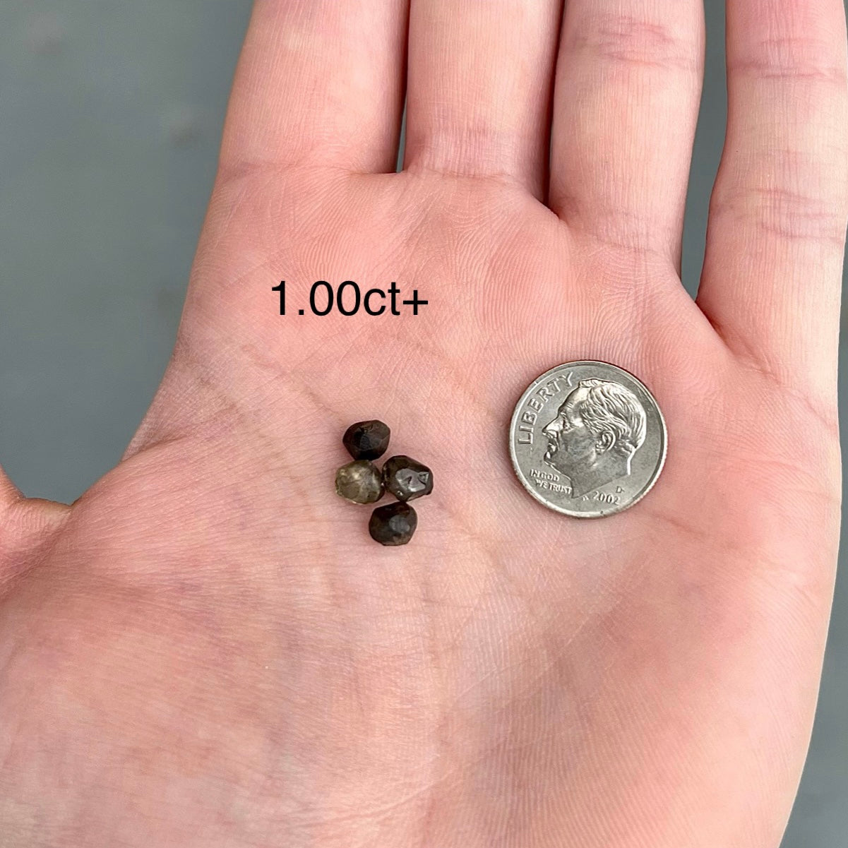 A selection of black diamond crystals of over a carat next to a dime.