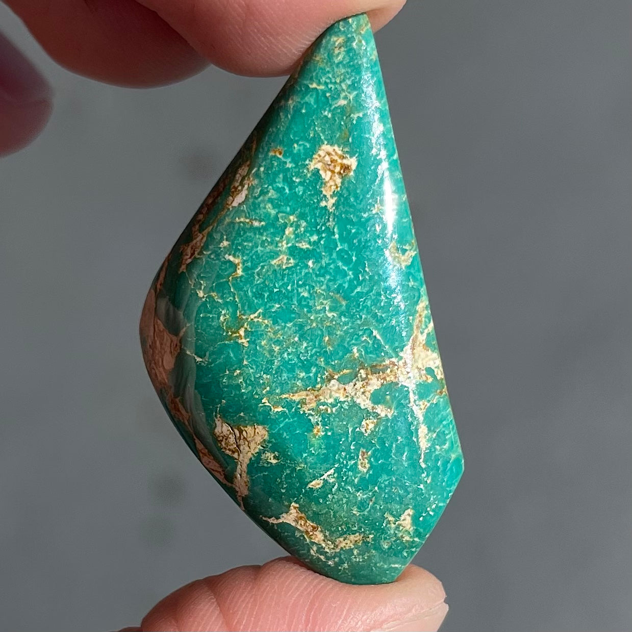 A loose, freeform cabochon cut green turquoise stone from Royston Mining District, Nevada.