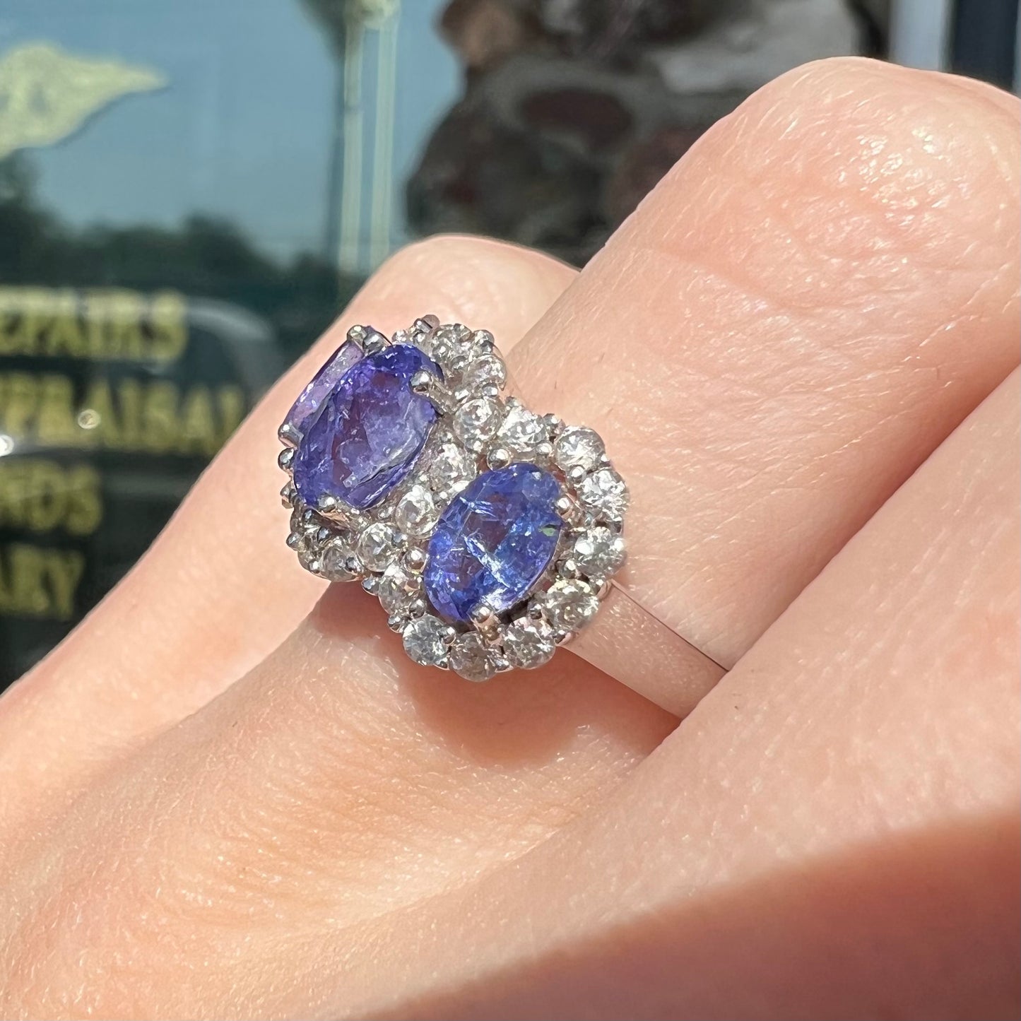A sterling silver past, present, future three stone tanzanite ring. The main stones are set in a halo of cubic zirconia.