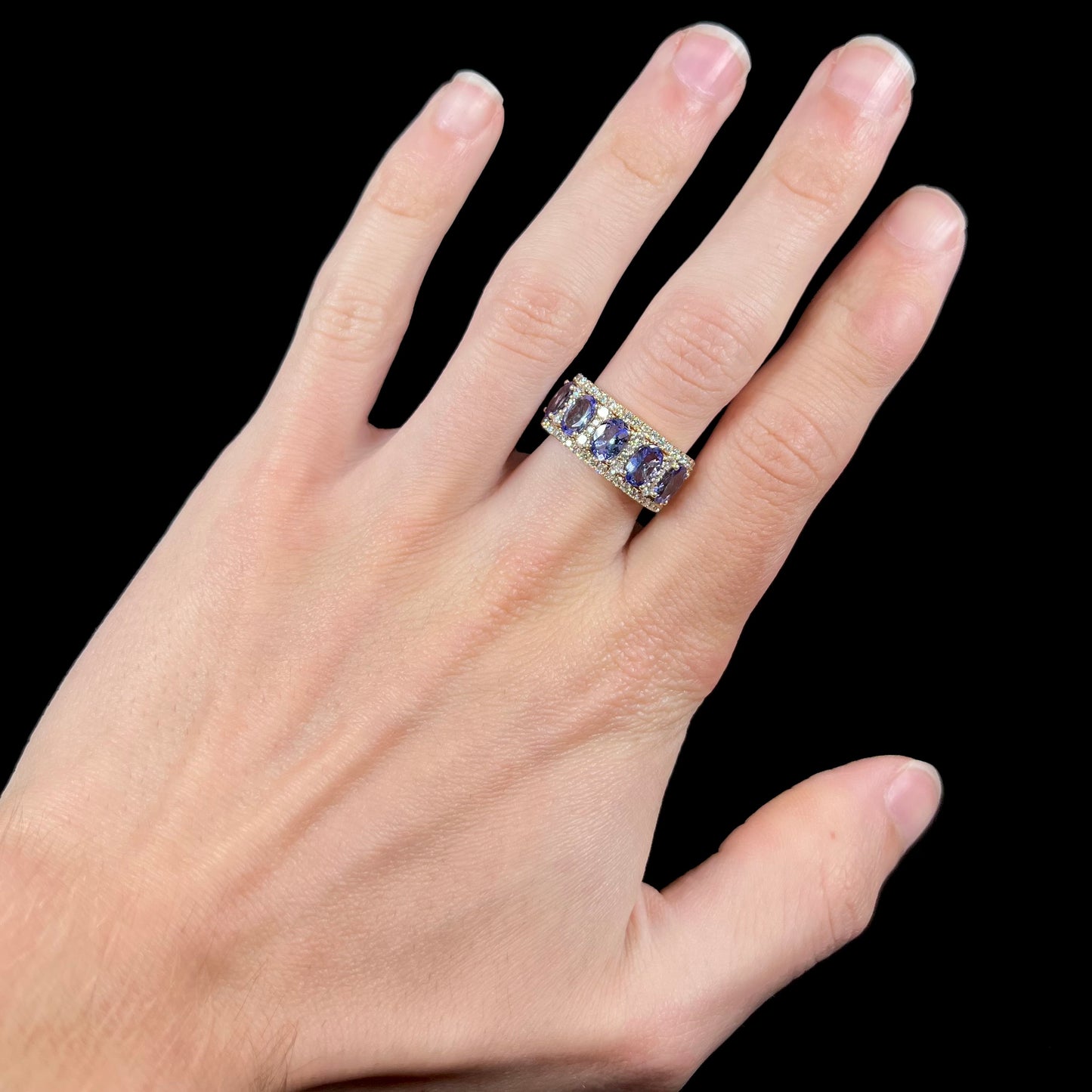 A gold and diamond ladies' band set with five oval cut tanzanite stones.