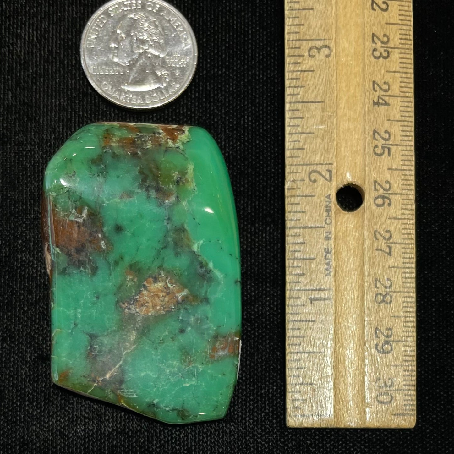 A polished green chrysoprase stone with brown matrix inclusions.