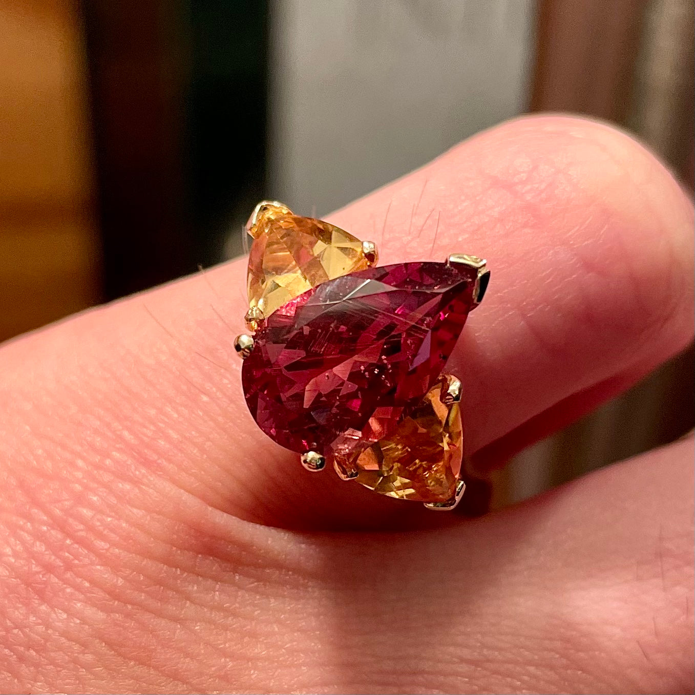 A gold ring set with a pear shape color change garnet between two trillion cut citrine accent stones.