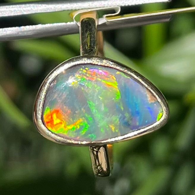 A freeform cut semi-black opal from Lightning Ridge, Australia set in a bezel set yellow gold solitaire ring.