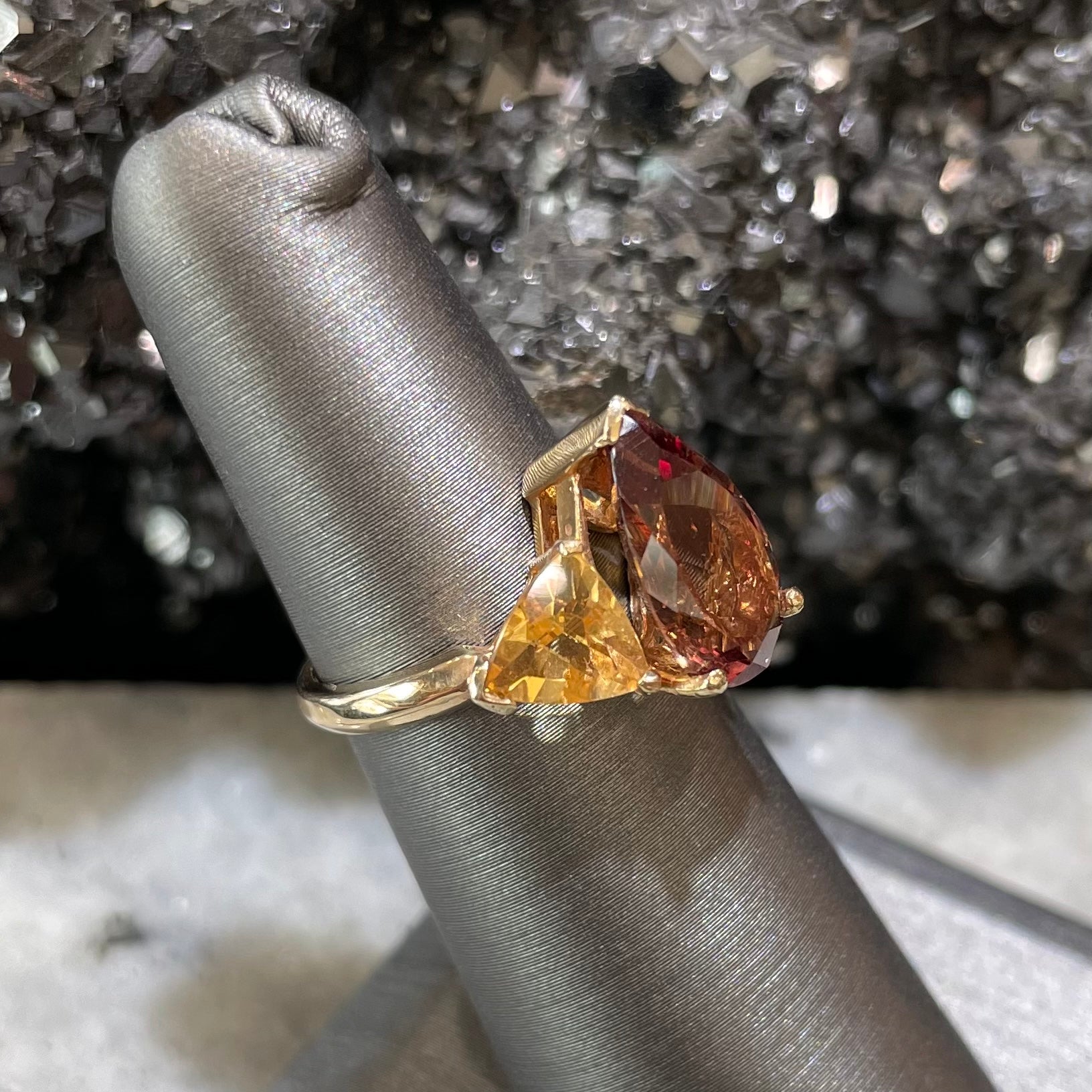 A gold ring set with a pear shape color change garnet between two trillion cut citrine accent stones.