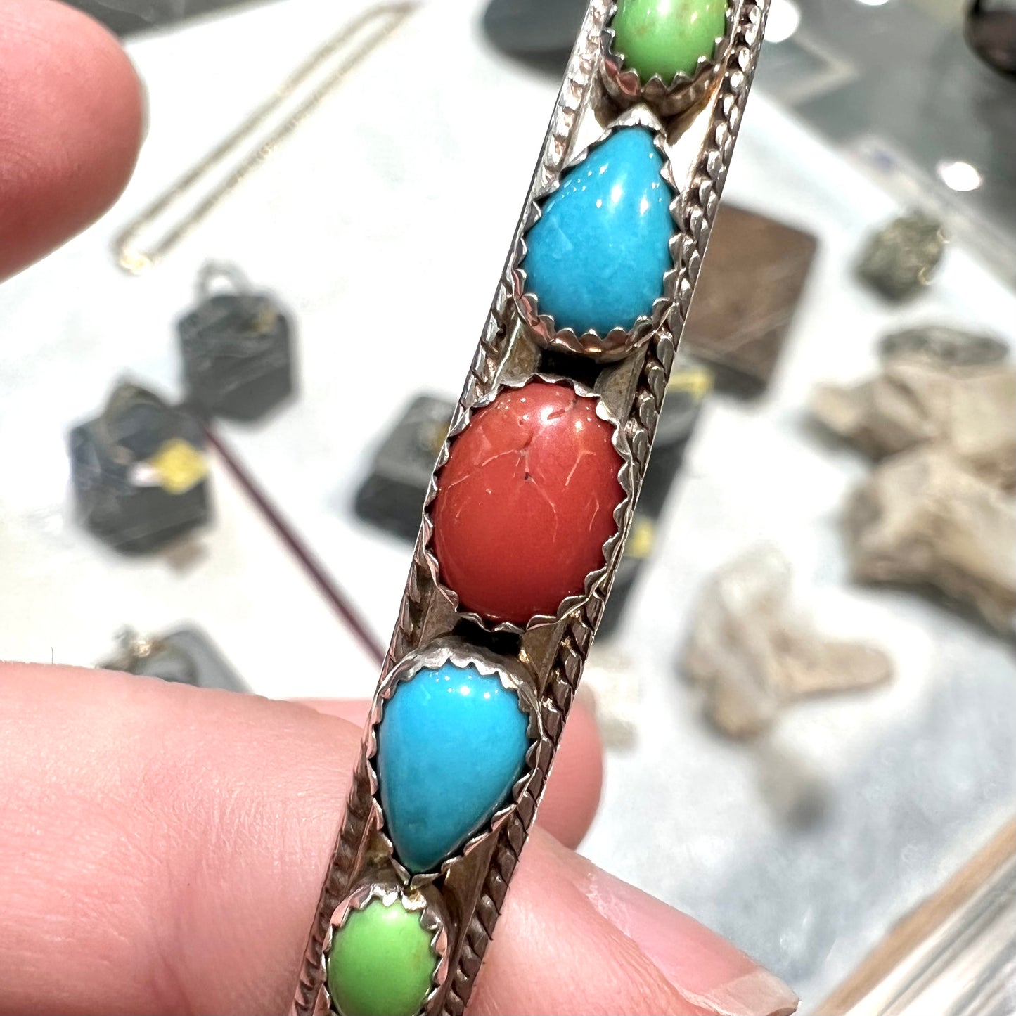 A silver rope cuff bracelet set with coral, turquoise, gaspeite, and lapis lazuli stones. The underside is stamped "Daniel Mike".
