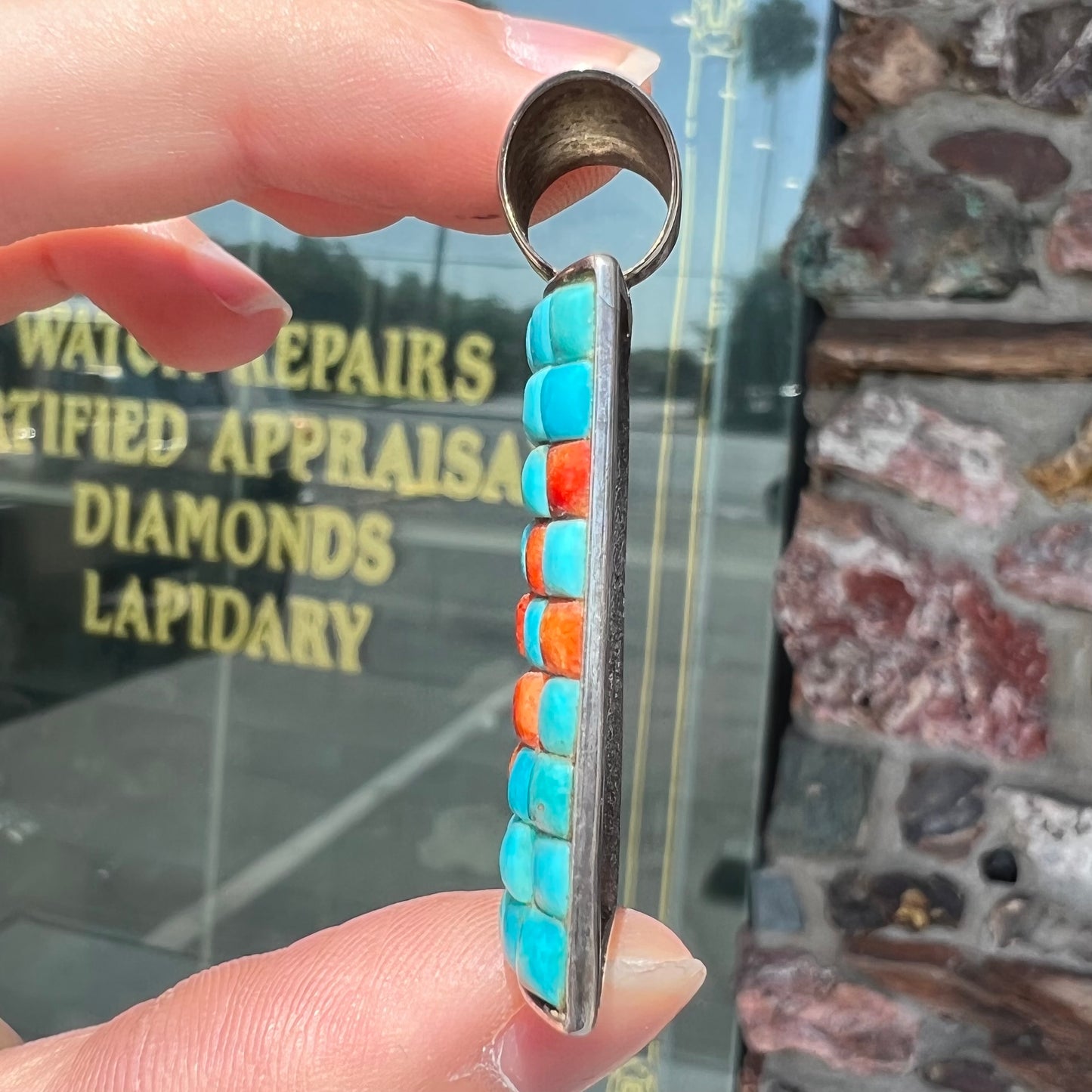 A silver pendant set with square cabochon cut turquoise and coral stones. The piece is stamped "DTR CHINA".