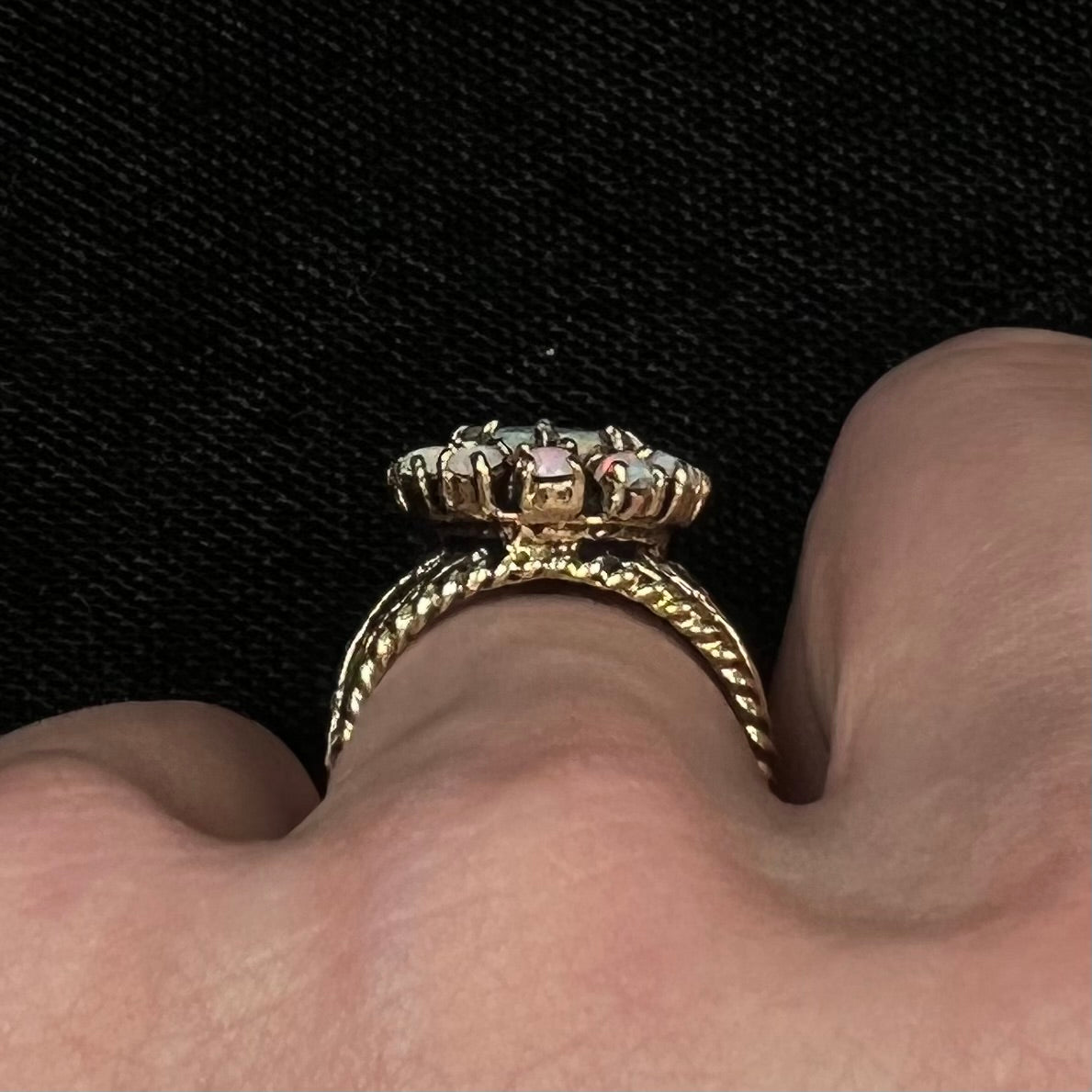 Vintage yellow gold oval opal cabochon ring set with 12 round opals in a halo around the center stone.