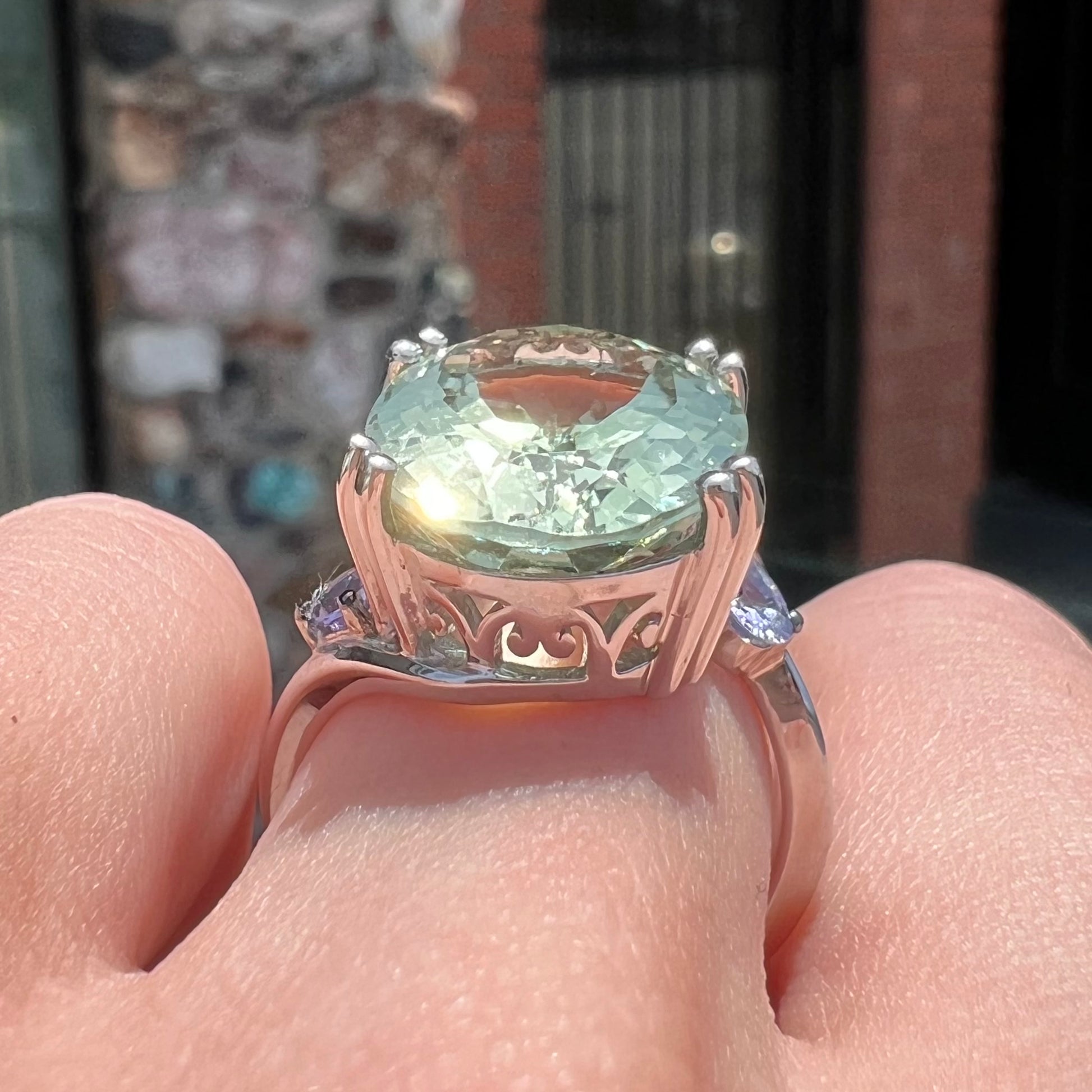 A sterling silver oval cut prasiolite ring set with two pear shaped tanzanite accent side stones.