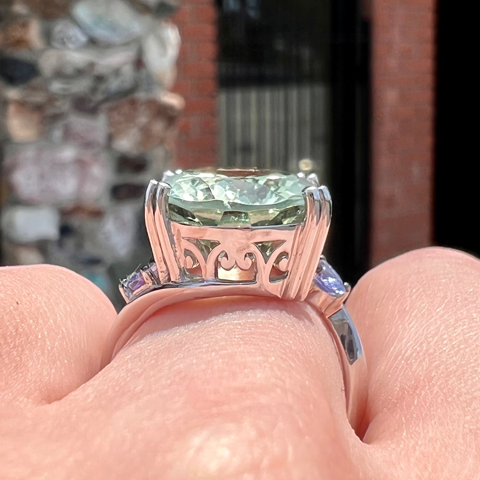 A sterling silver oval cut prasiolite ring set with two pear shaped tanzanite accent side stones.