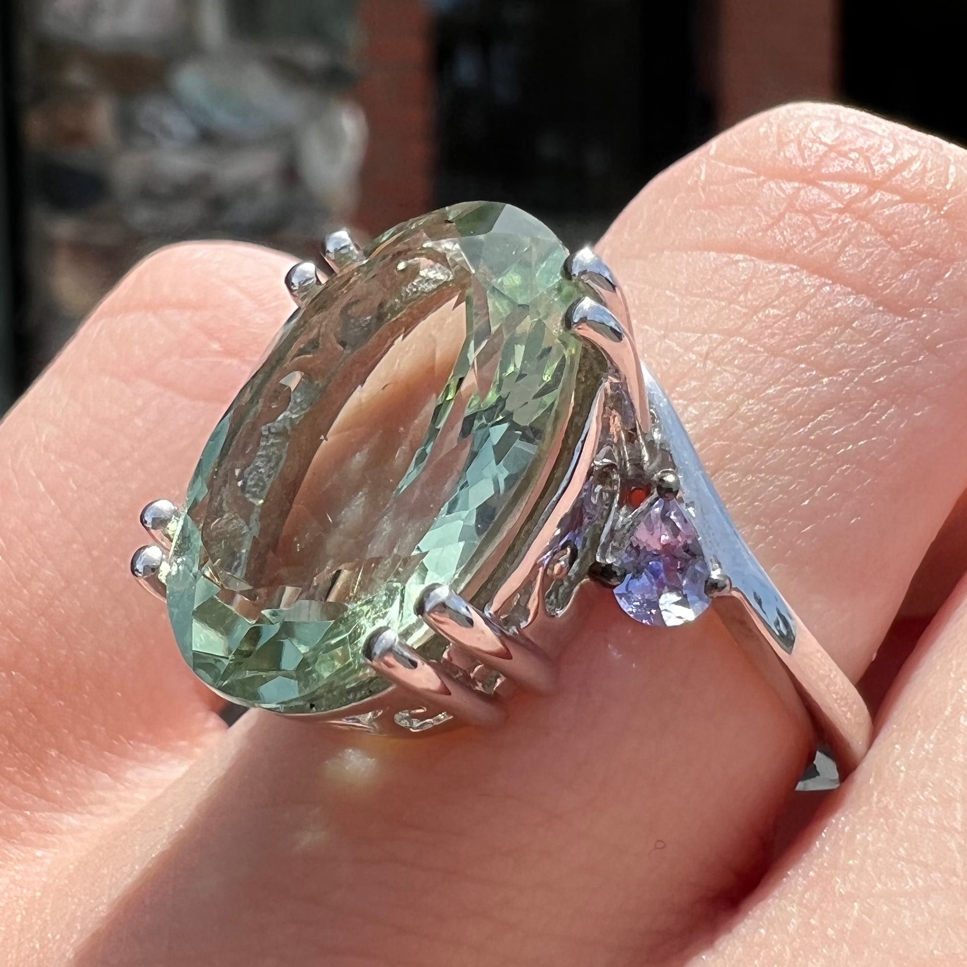 A sterling silver oval cut prasiolite ring set with two pear shaped tanzanite accent side stones.