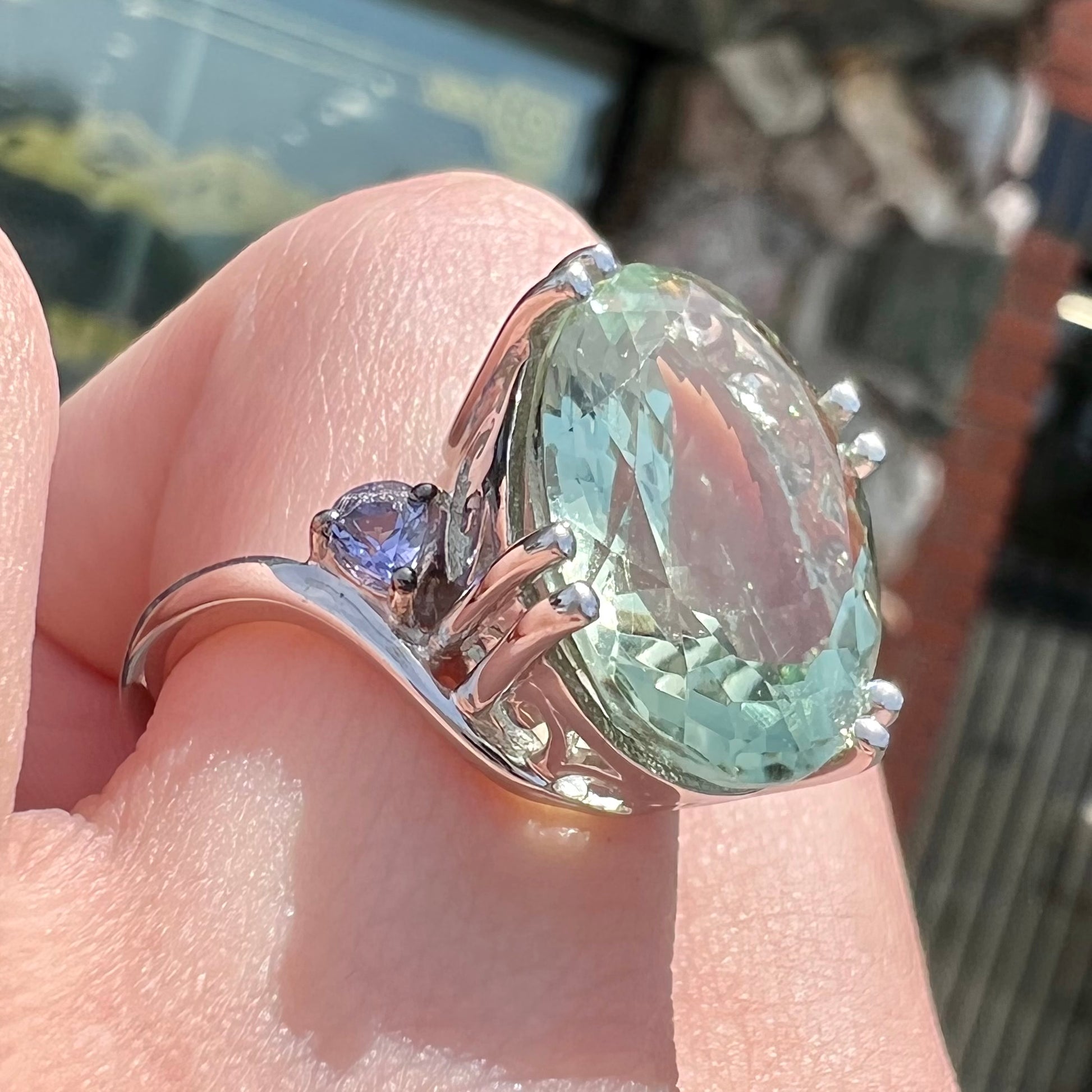 A sterling silver oval cut prasiolite ring set with two pear shaped tanzanite accent side stones.