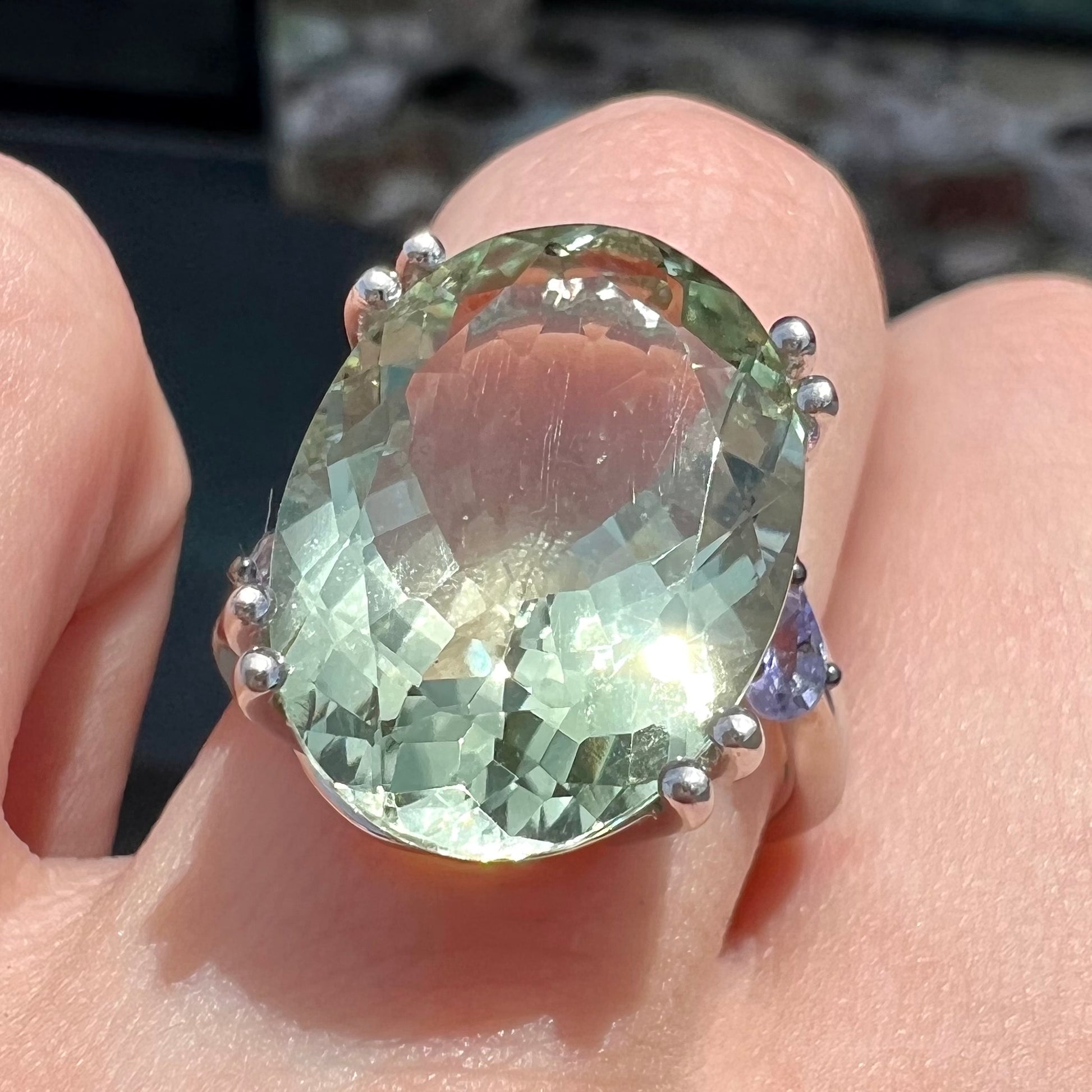 A sterling silver oval cut prasiolite ring set with two pear shaped tanzanite accent side stones.