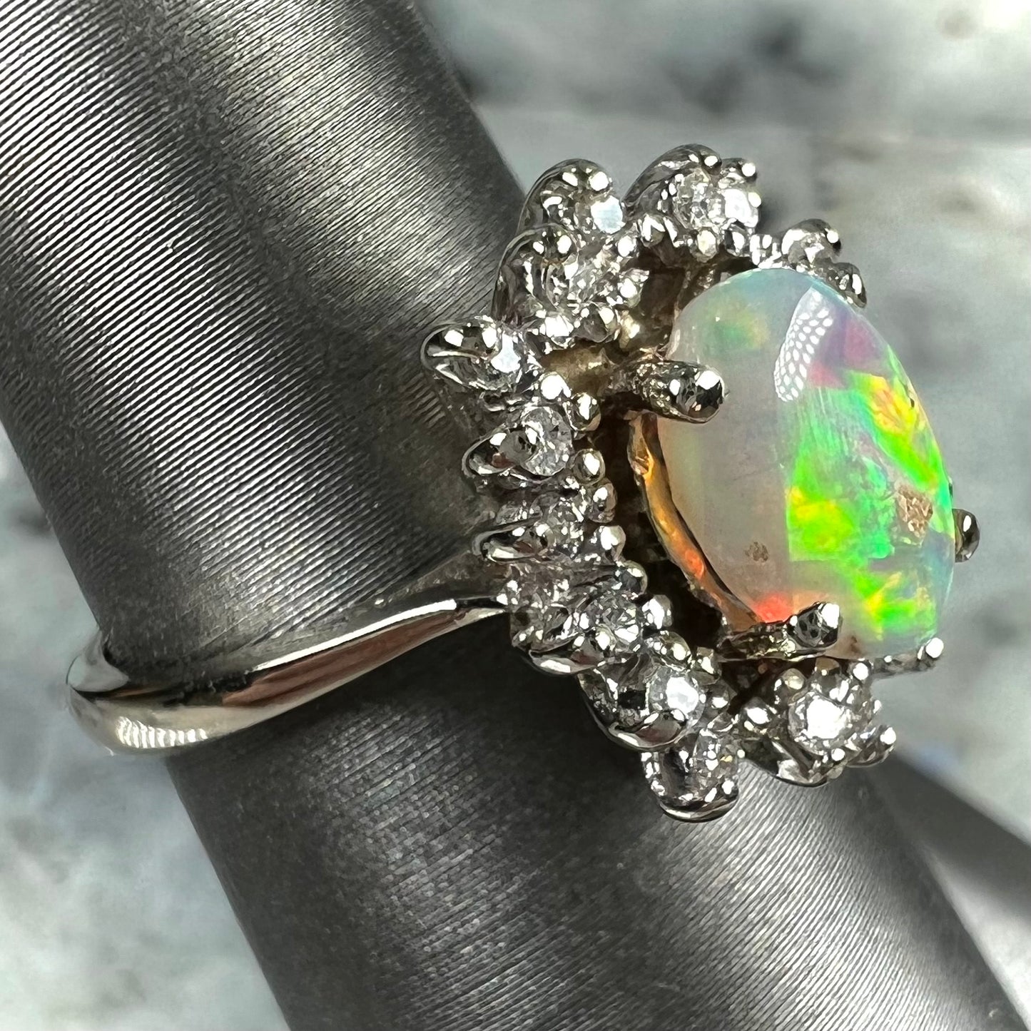 A white crystal opal ring cast in white gold with a halo of round cut diamonds.