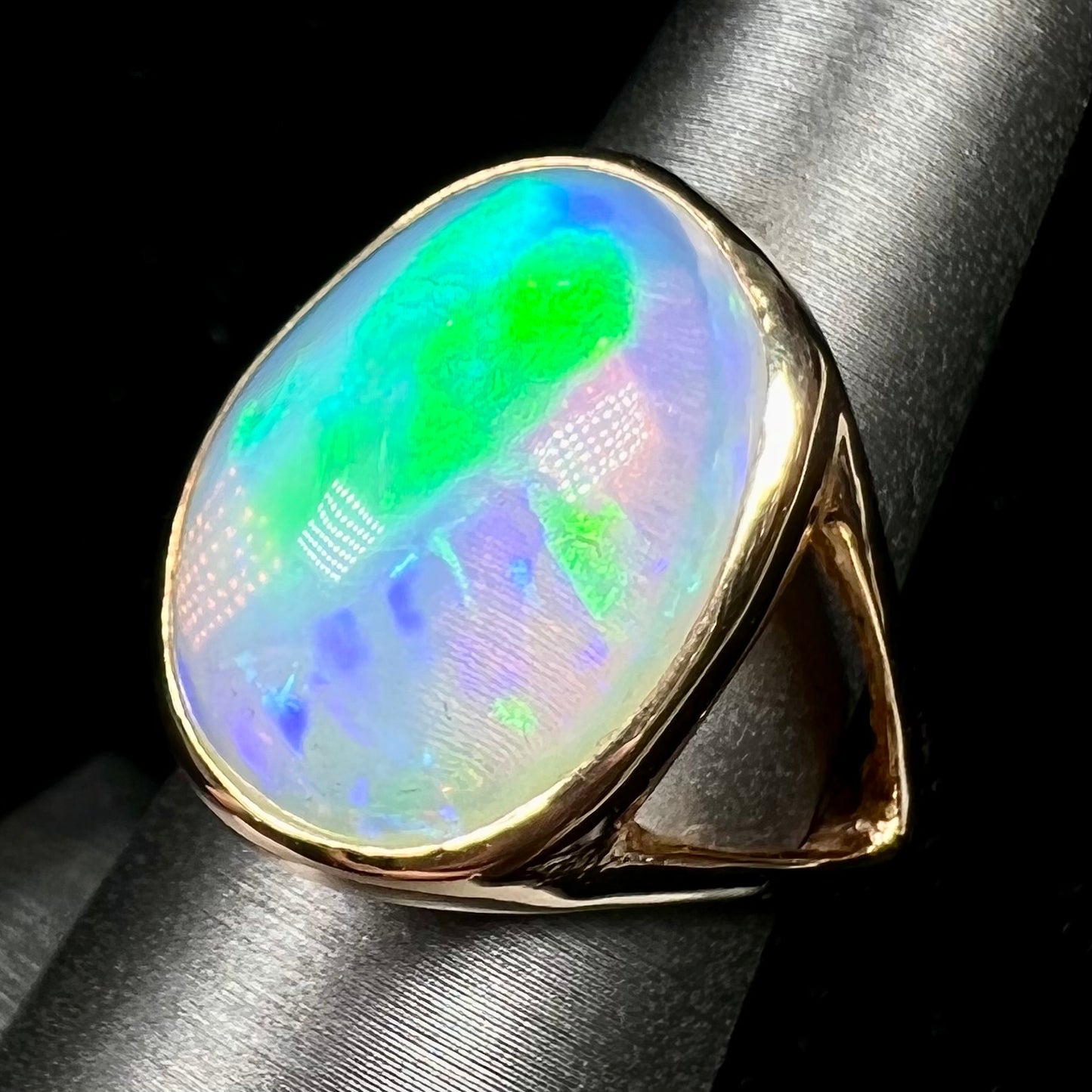 A gold split shank solitaire ring set with an oval cabochon cut 16.83 carat Ethiopian jelly fire opal.