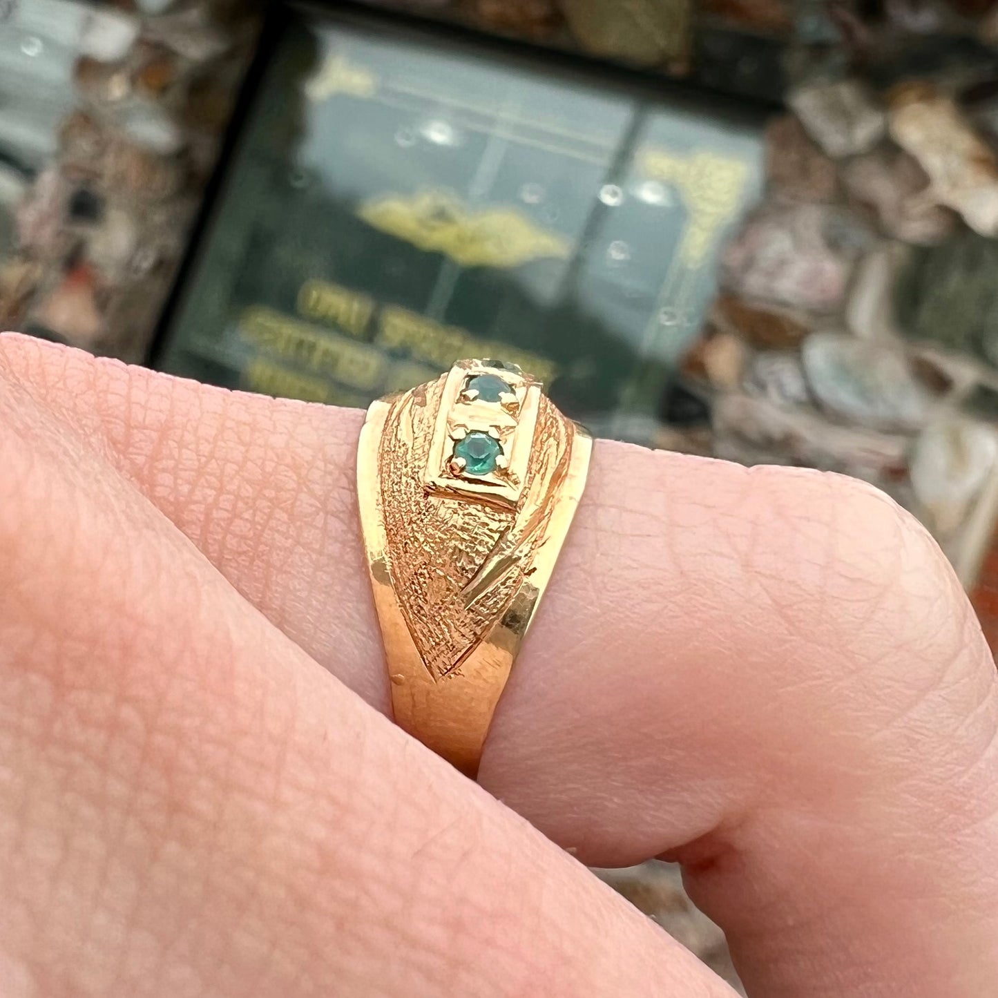 A 1920's style yellow gold three stone round cut emerald ring.