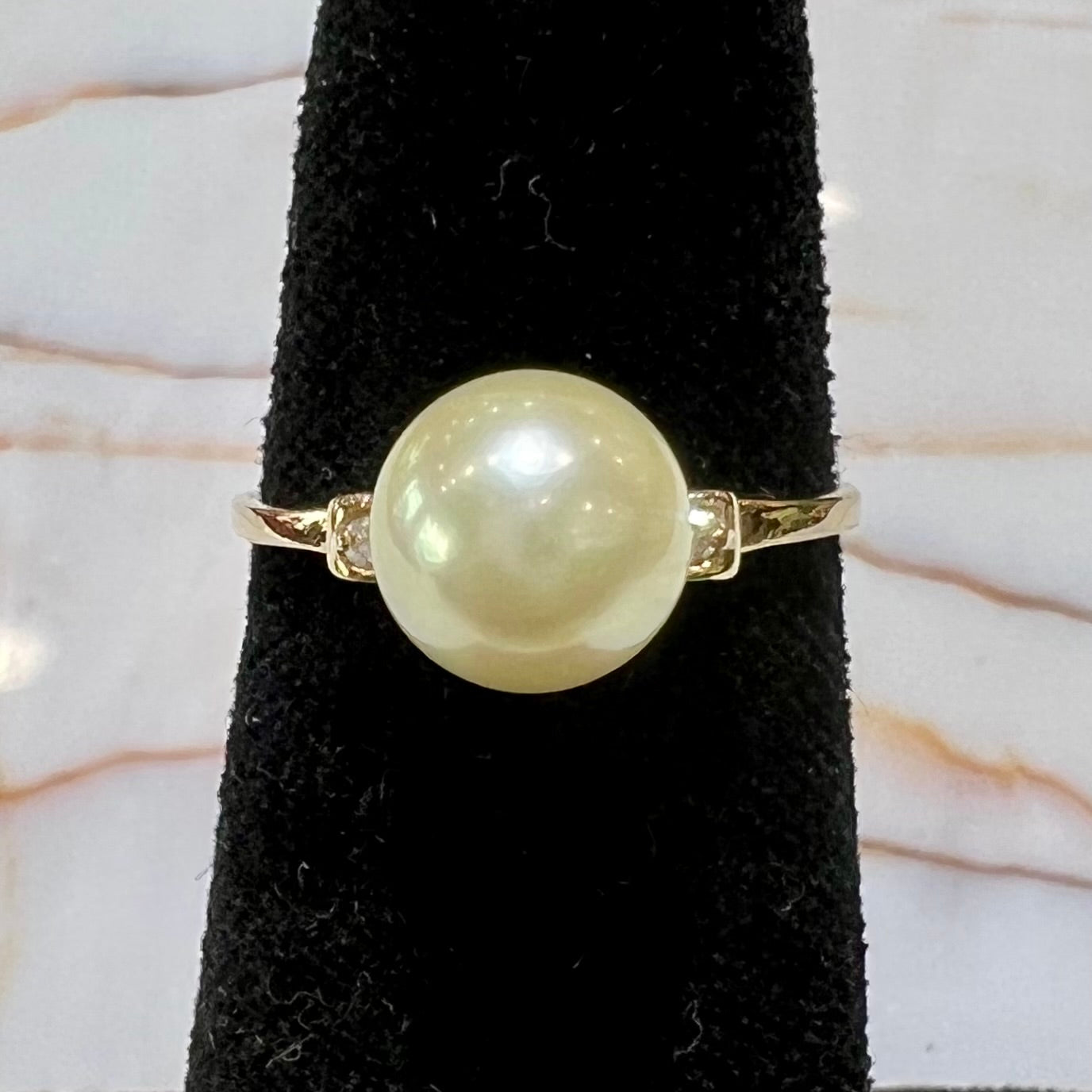 A simple, vintage, yellow gold pearl ring set with two side diamonds.