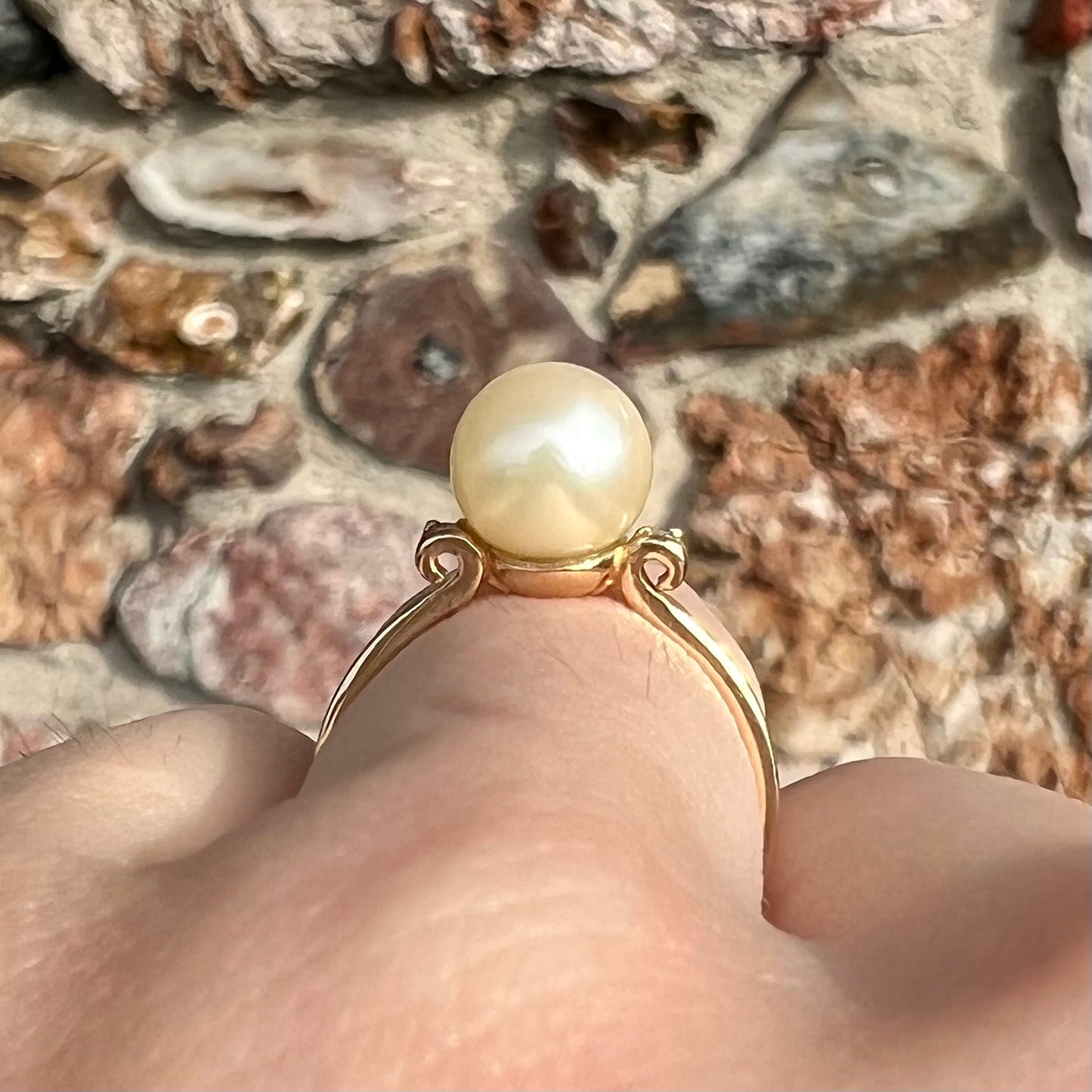 A simple, vintage, yellow gold pearl ring set with two side diamonds.