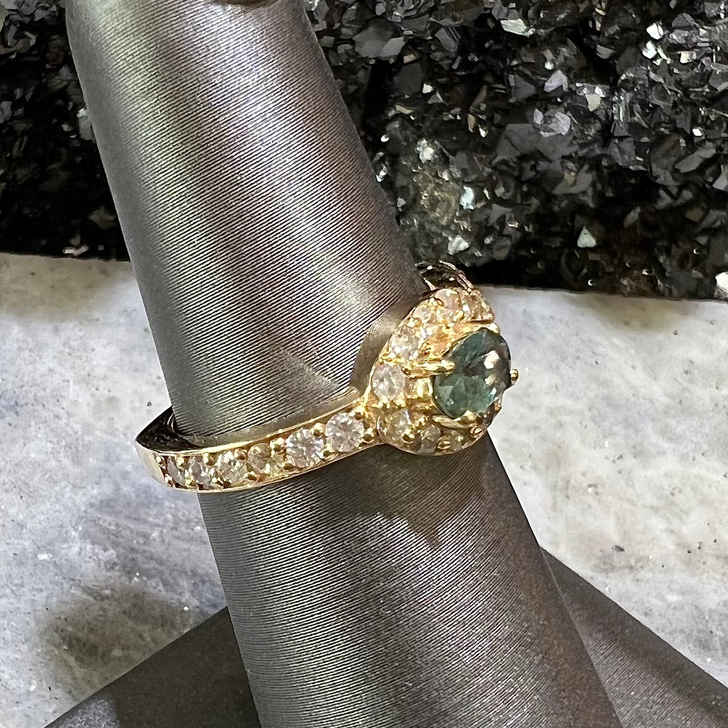 Yellow gold alexandrite and pave set diamond ladies' ring on ring stand.