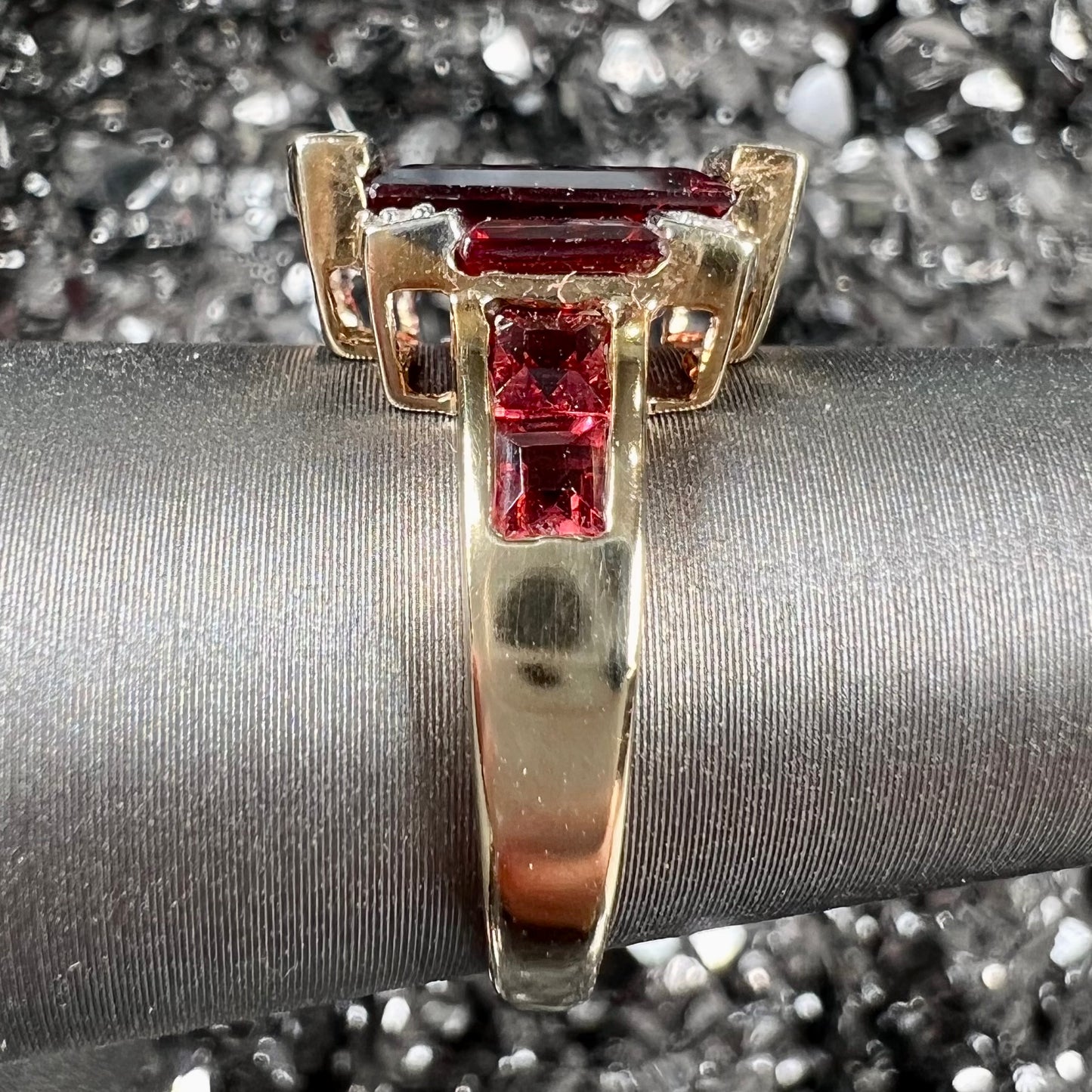An Art Deco style emerald cut garnet and diamond ring cast in yellow gold.