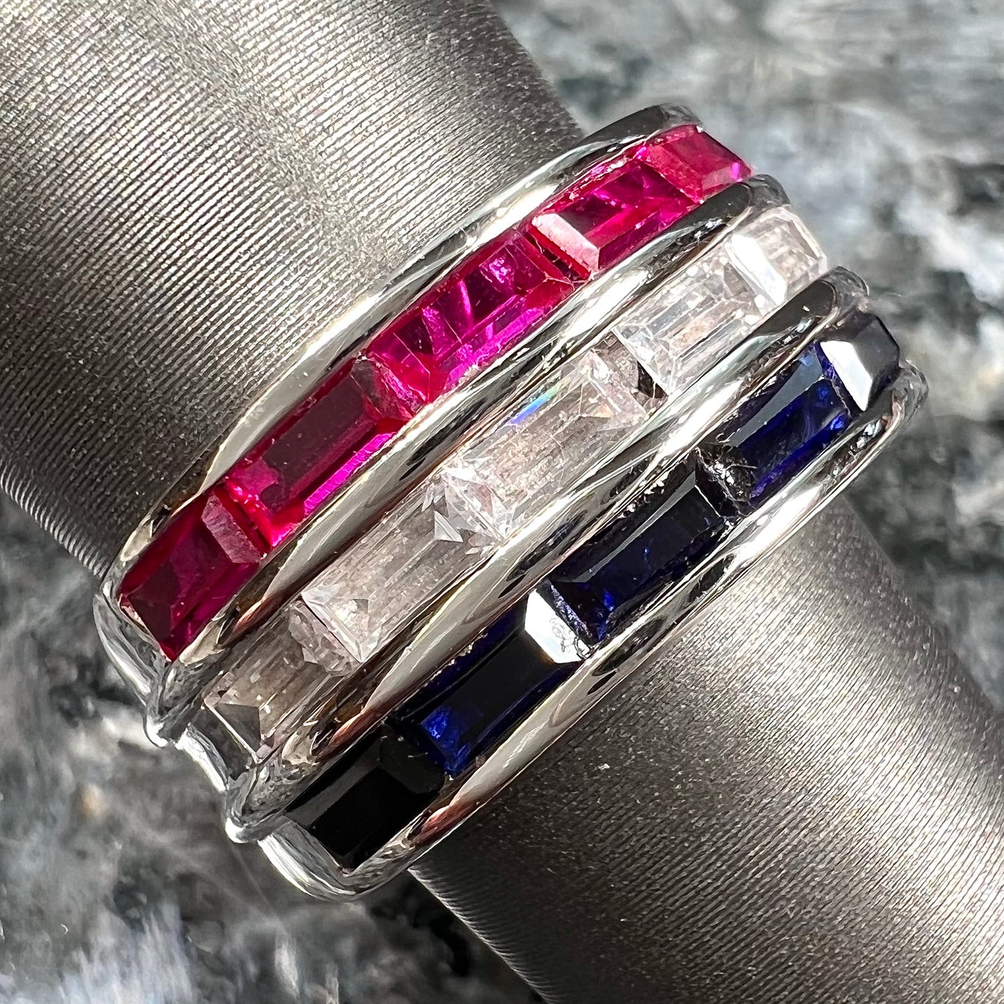 A silver ring set with red, white, and blue baguette cut stones.  The gallery features two stars.