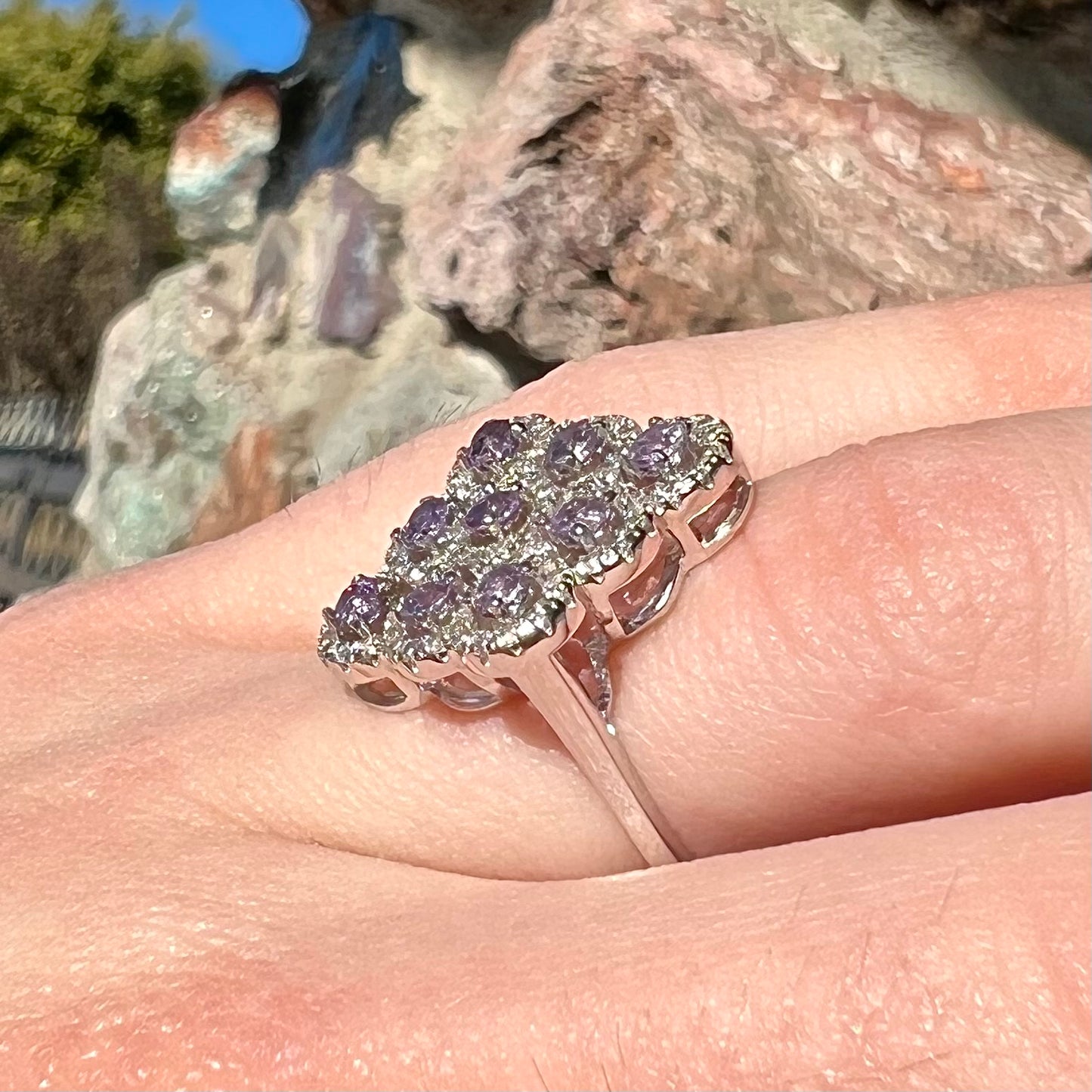 A silver ladies' ring set with 9 rose de France amethyst stones in white topaz halos.