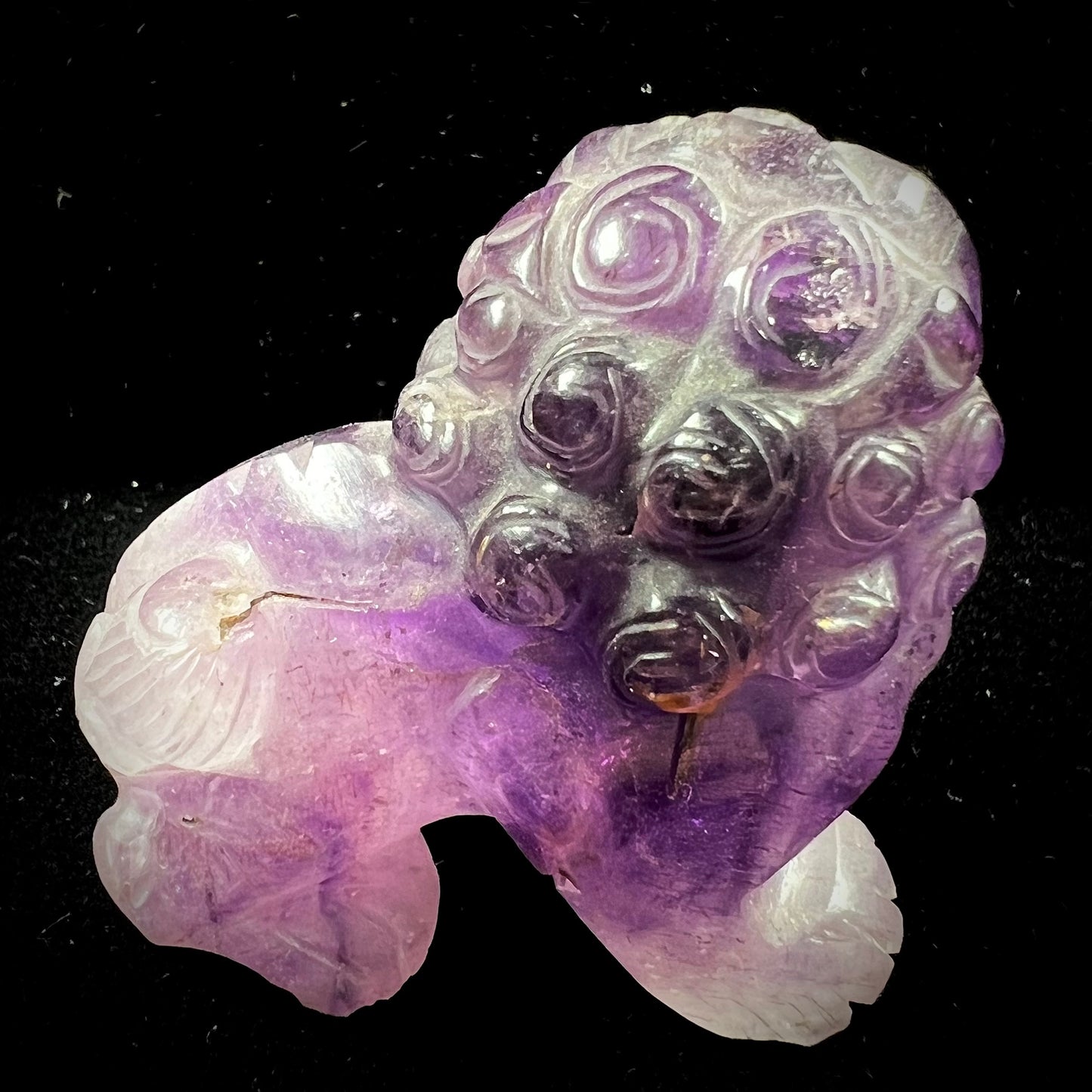 A stone foo dog carving carved from a purple Brazilian amethyst crystal.