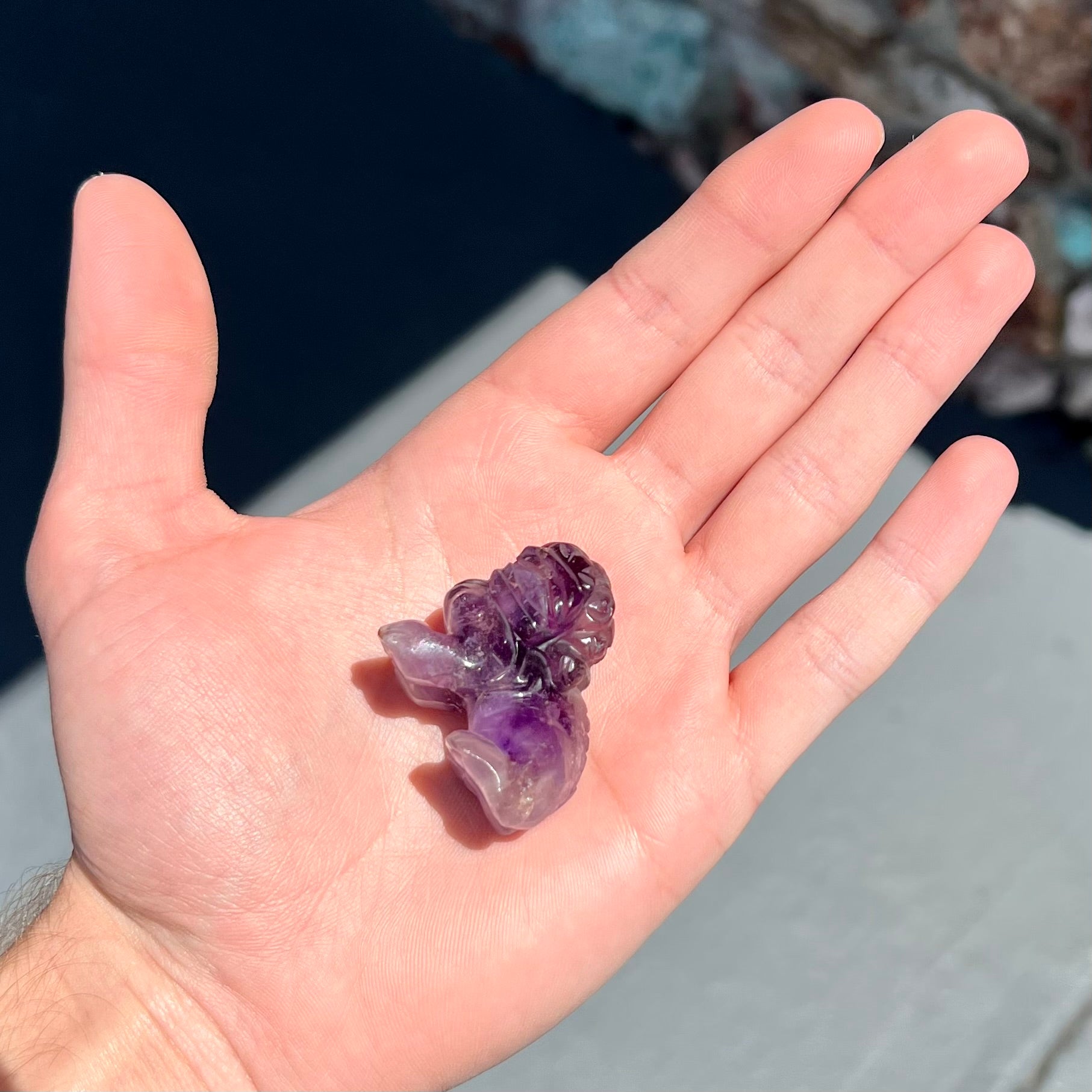 A stone foo dog carving carved from a purple Brazilian amethyst crystal.