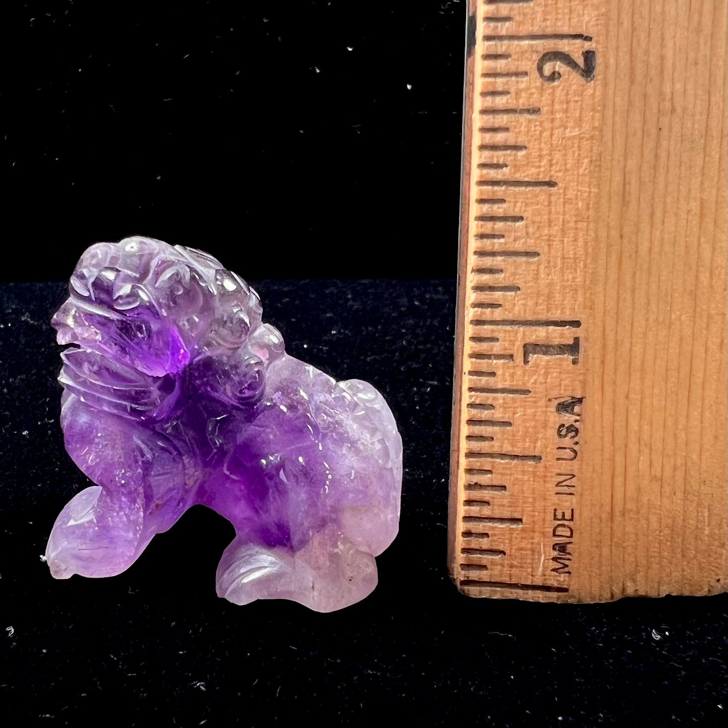 A stone foo dog carving carved from a purple Brazilian amethyst crystal.